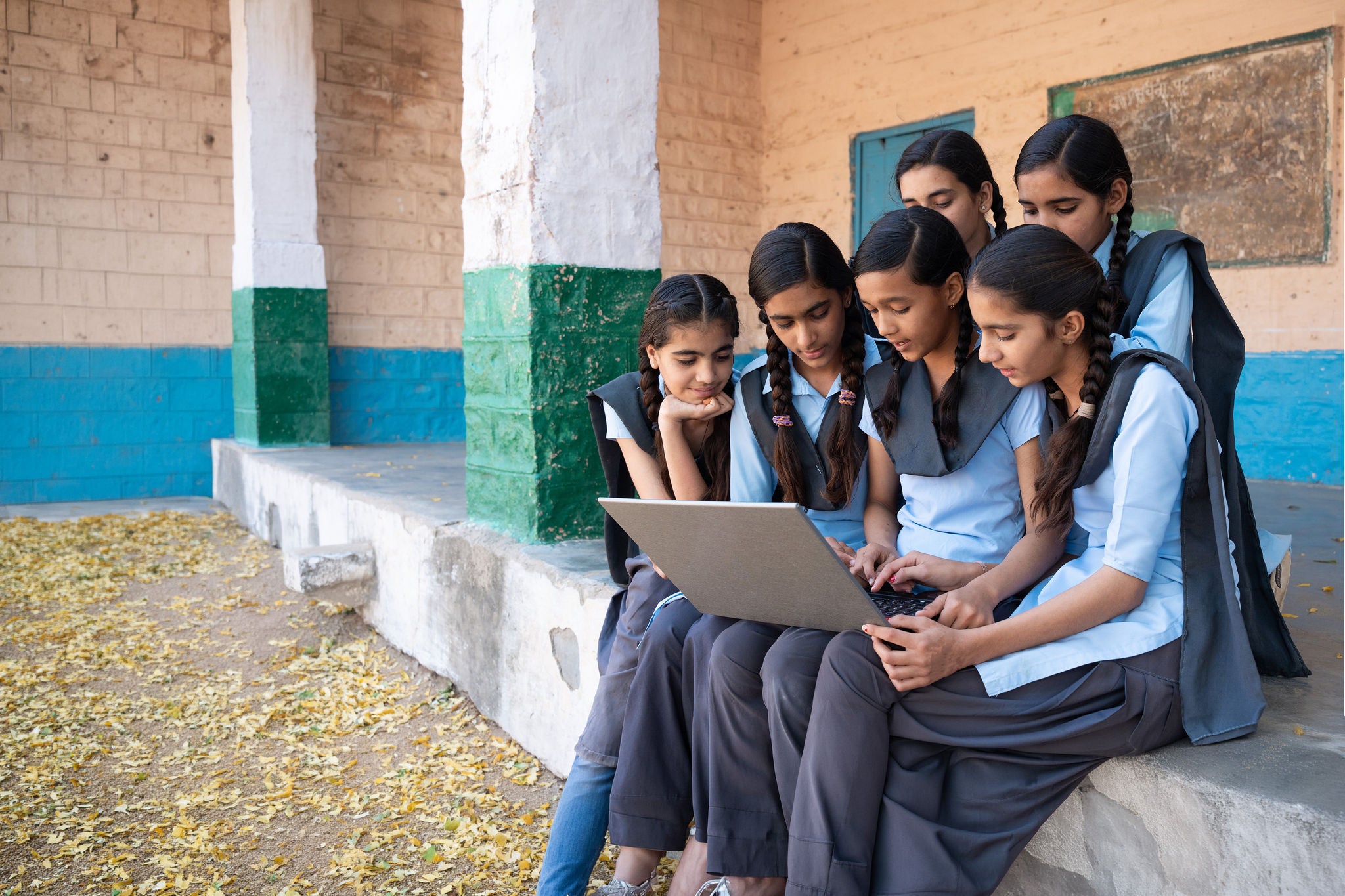 ey-gcc-school-students-collaboratively-learning-on-laptop-outside-rural-classroom-setting.jpg