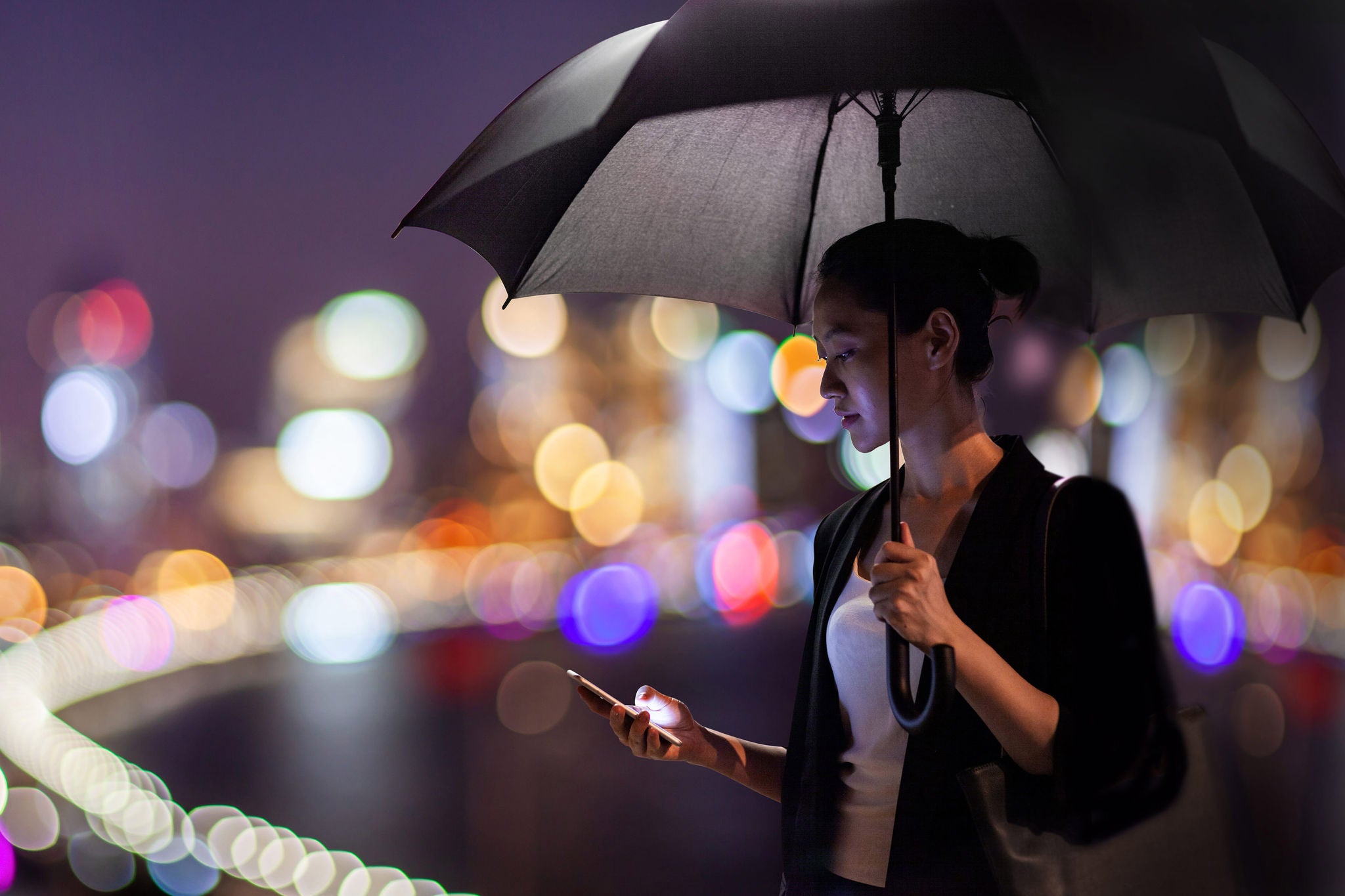 Woman holding an umbrella and using phone