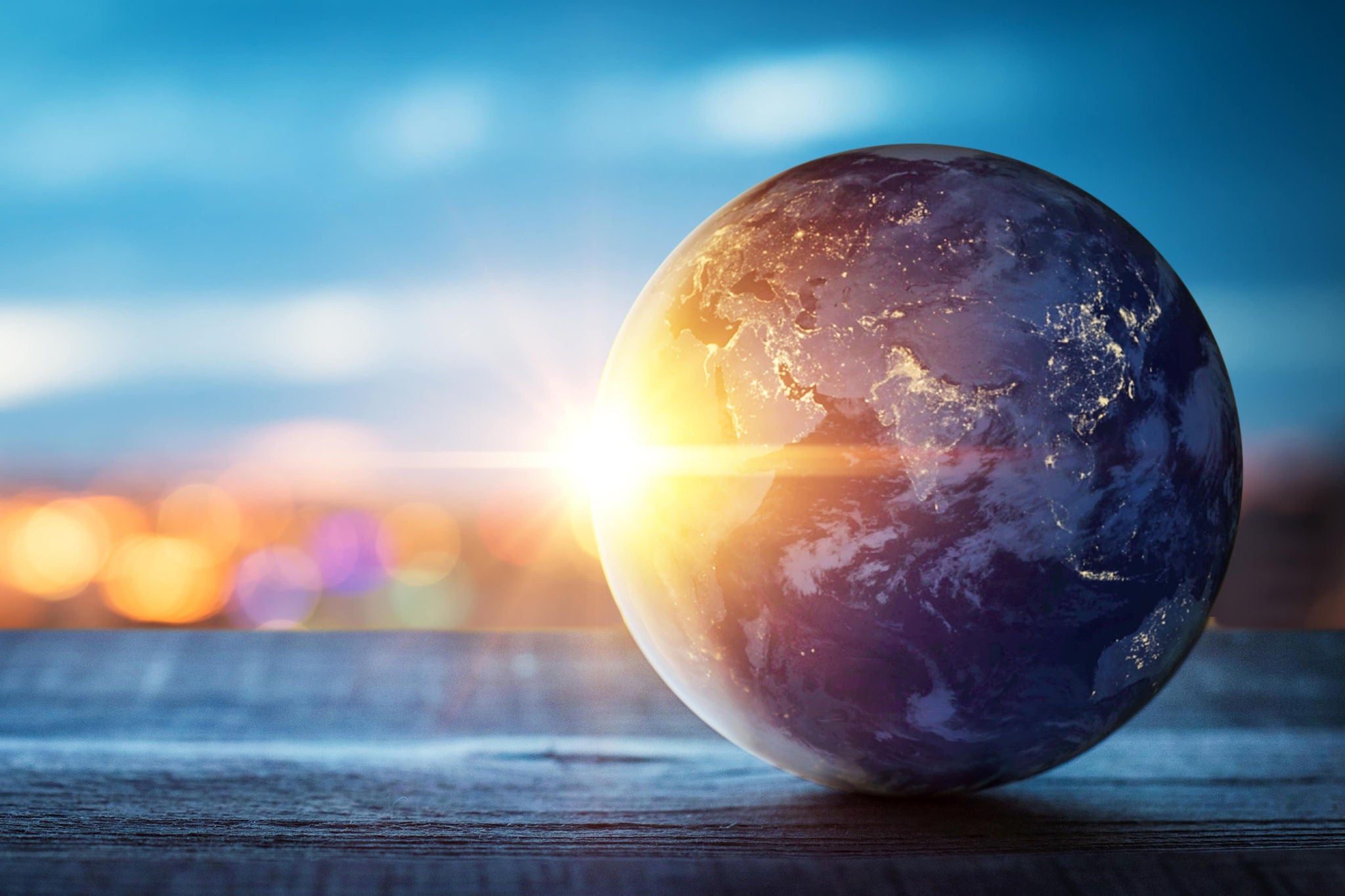 A smiling young woman with headphones and folders, standing outdoors on a college campus.