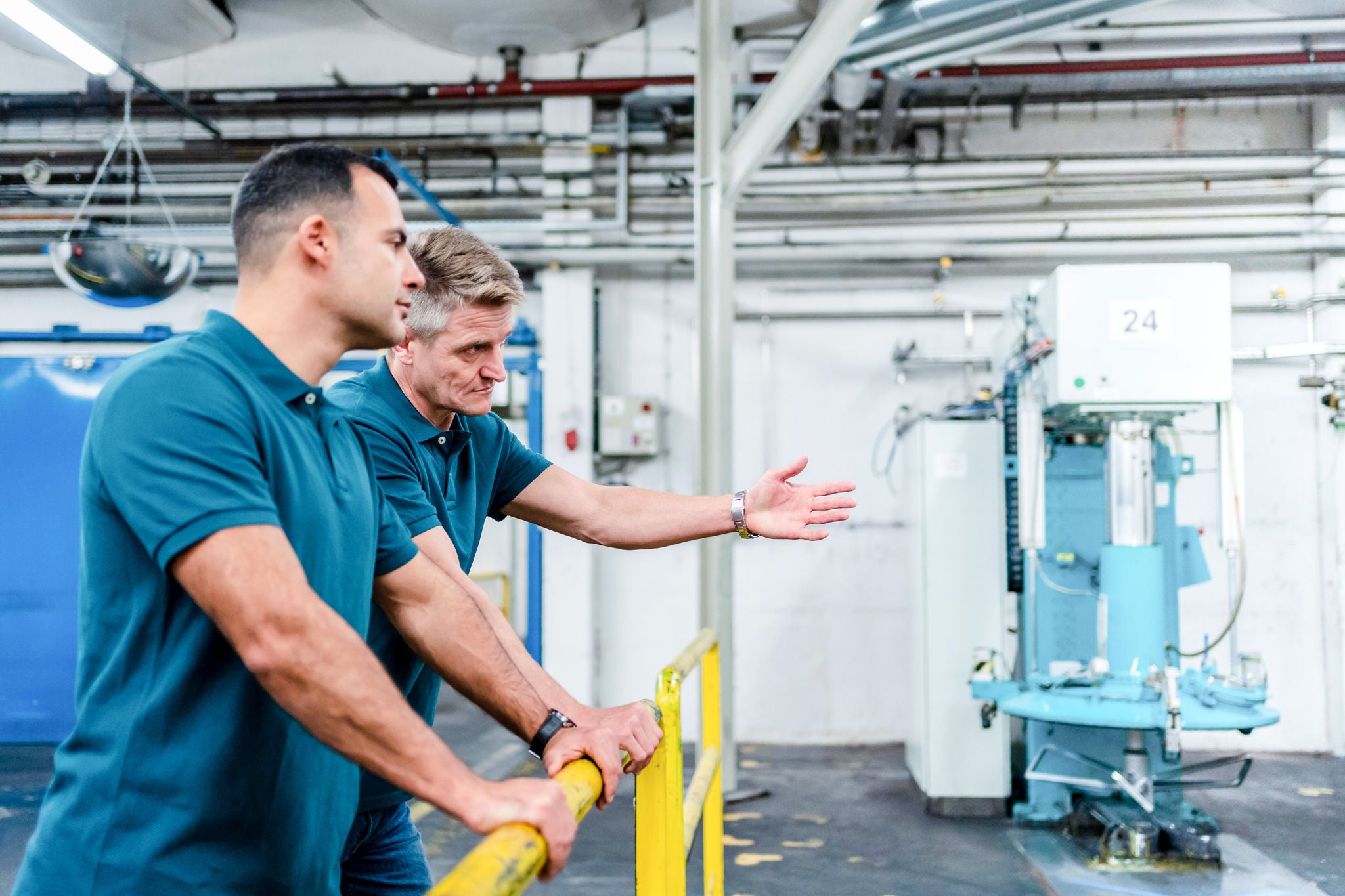 Ein Maennliche Techniker zeigt mit der Hand auf etwas während er mit seinem Kollegen spricht