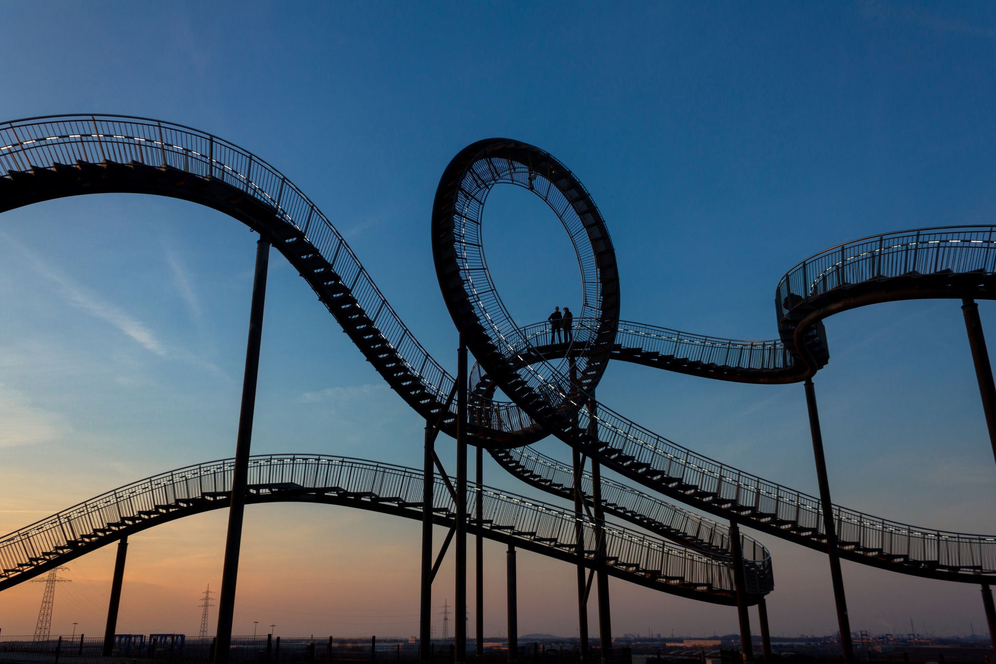 Two people stand on curved stairs at dusk