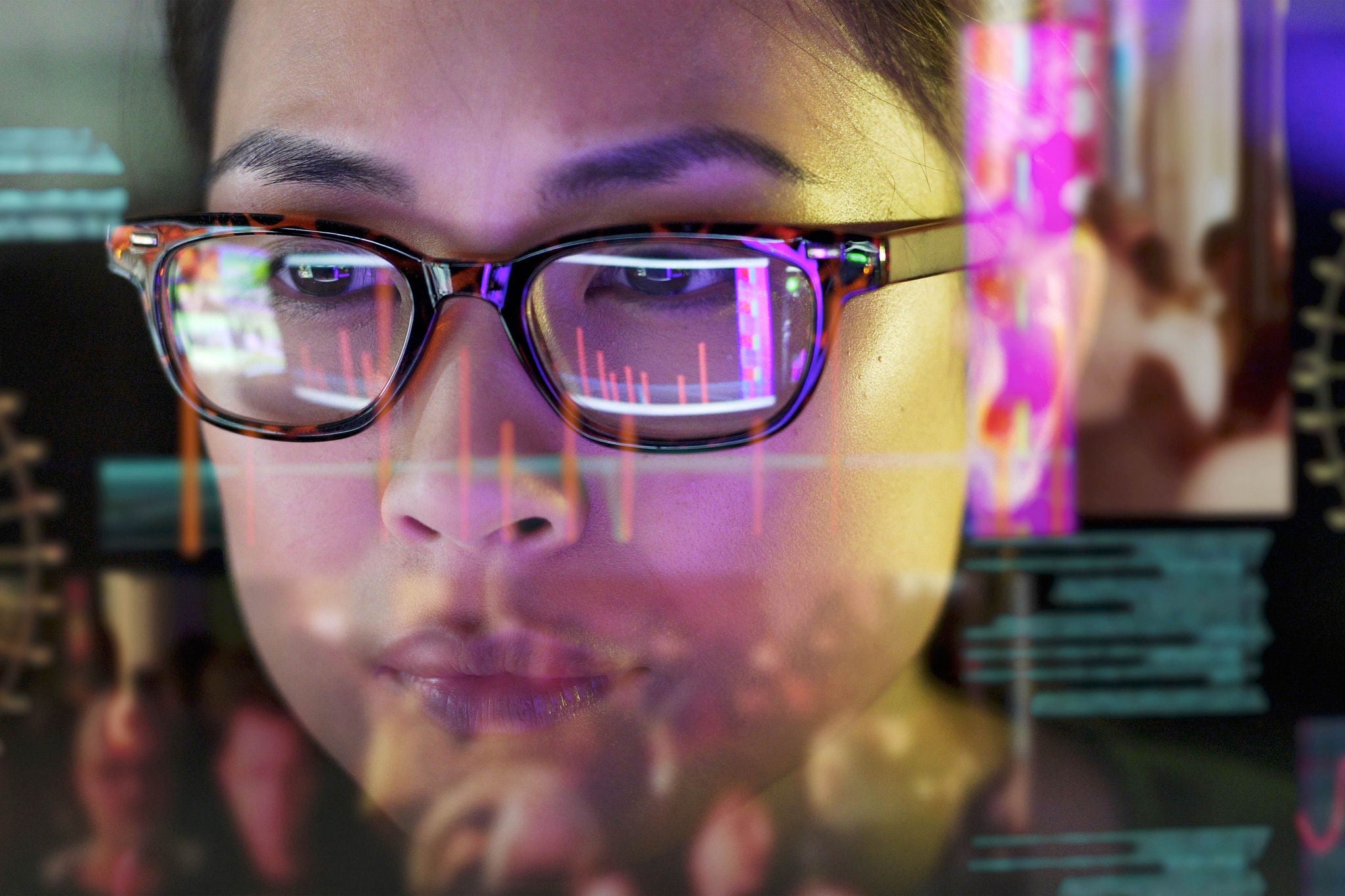 Close up stock photo of an Asian woman carefully studying moving data on her computer screen