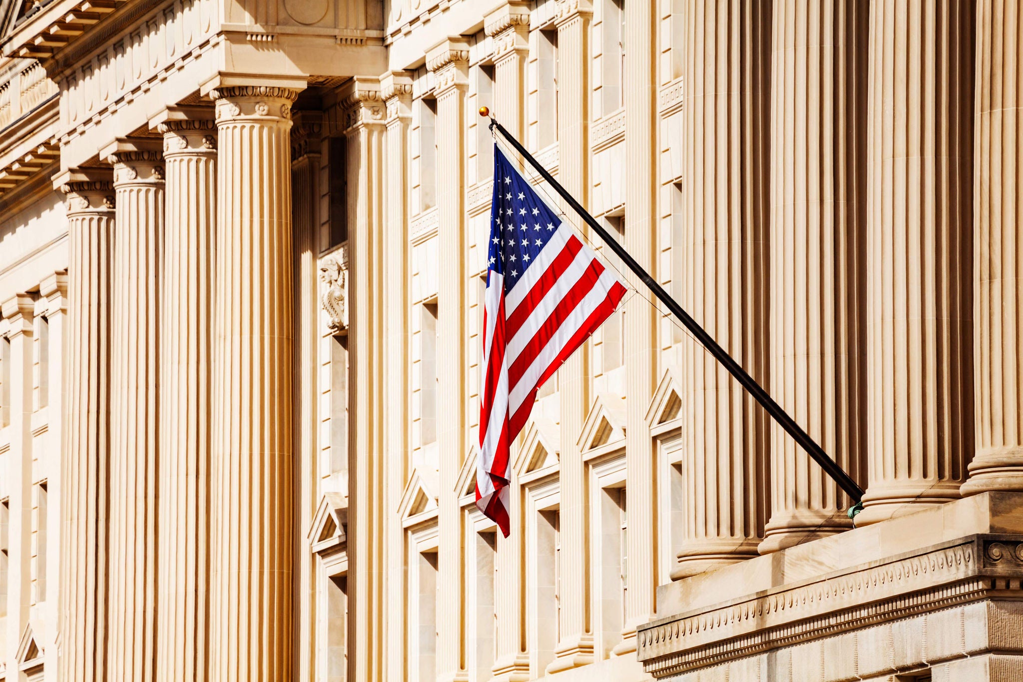 US flag over classical government building with columns in Washington, DC