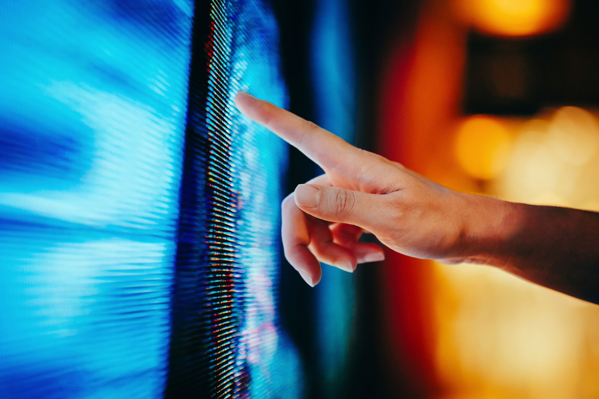 Doigt touchant un écran numérique avec des pixels colorés et lumineux