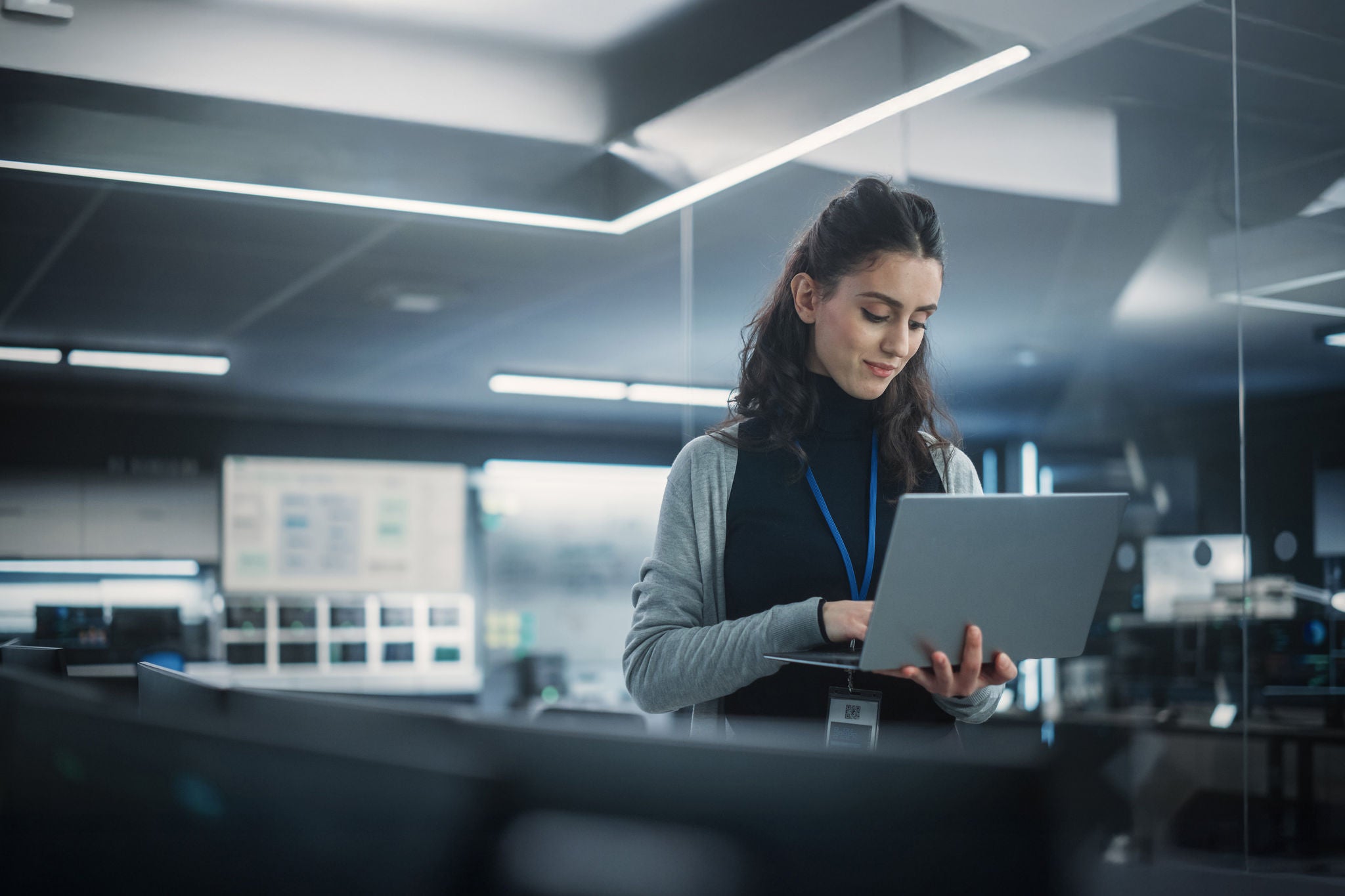 Person arbeitet mit Laptop in einer modernen, technologie­getriebenen Büroumgebung.