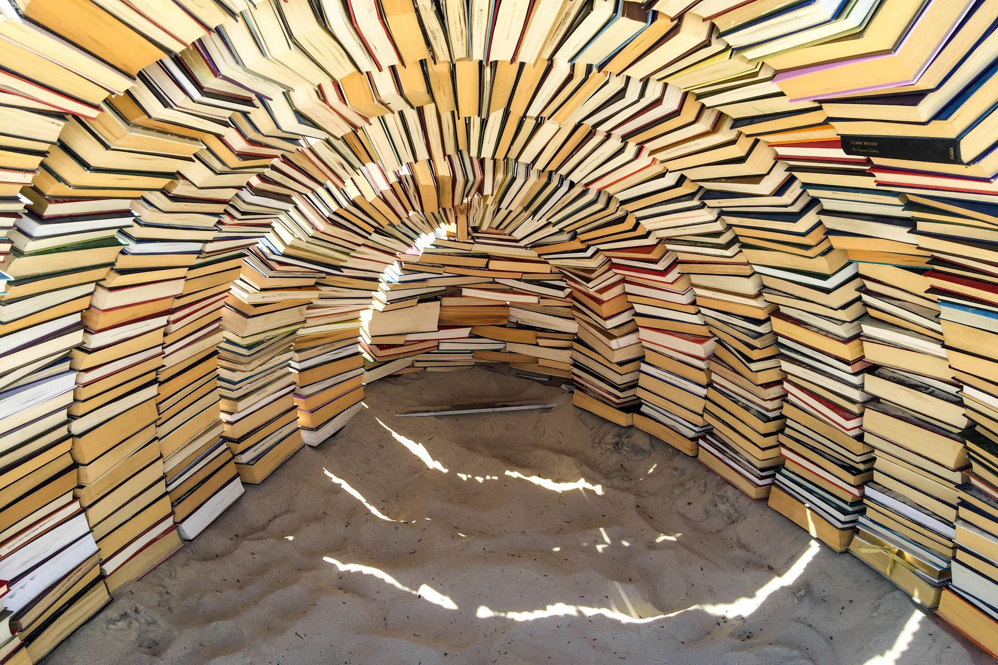 EY an art installation cave made of books on a beach