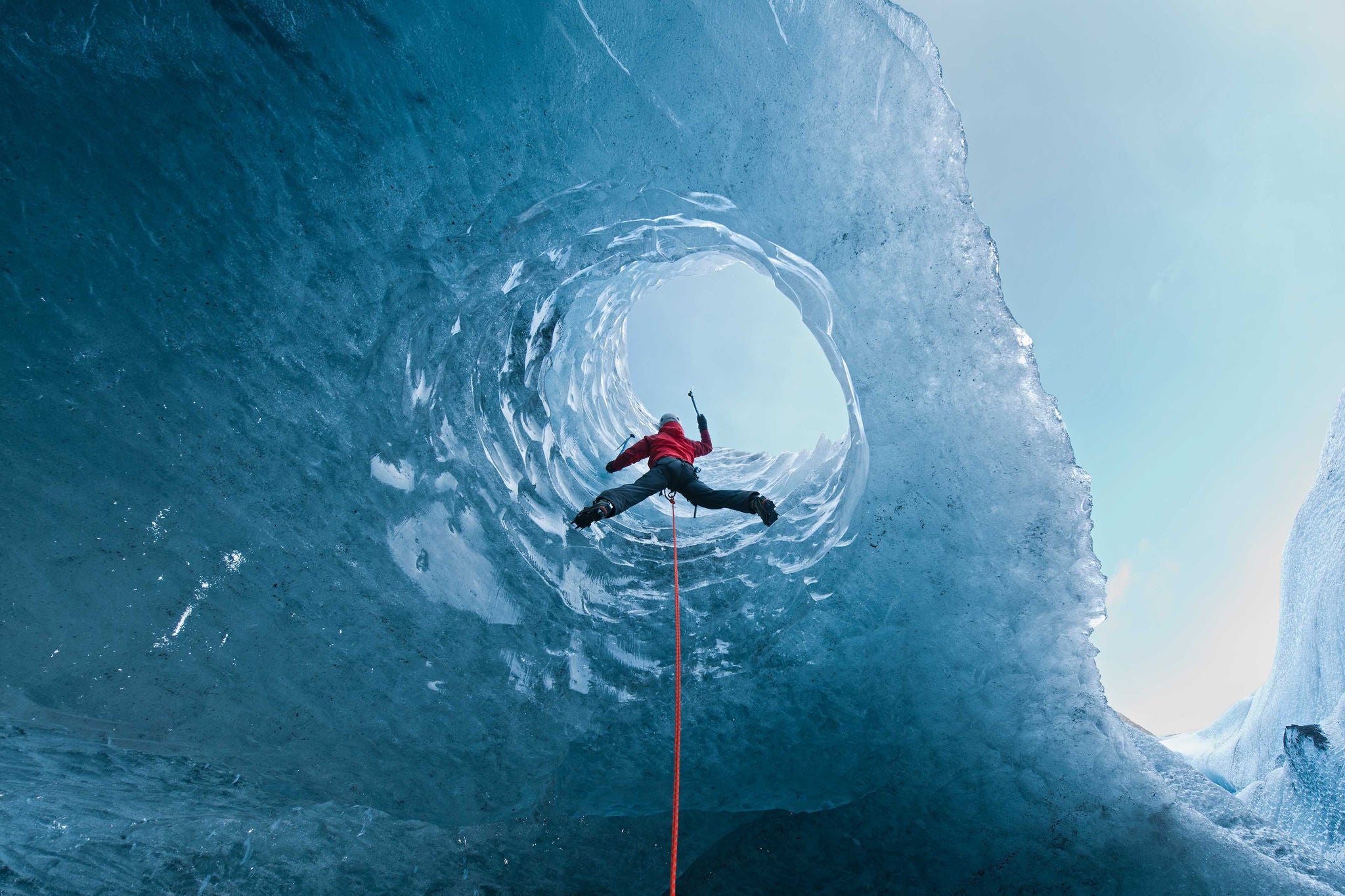 Woman climbing out of glacier cave, Slheimajkull Galcier, Iceland 