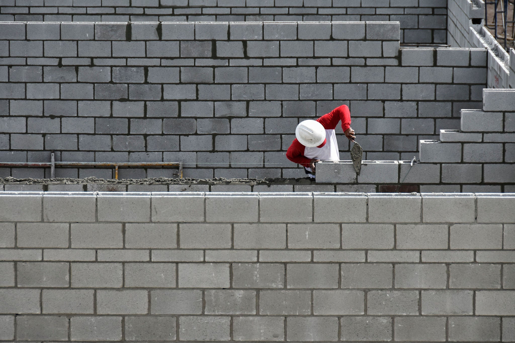 A man constructs a brick wall with brick layers.