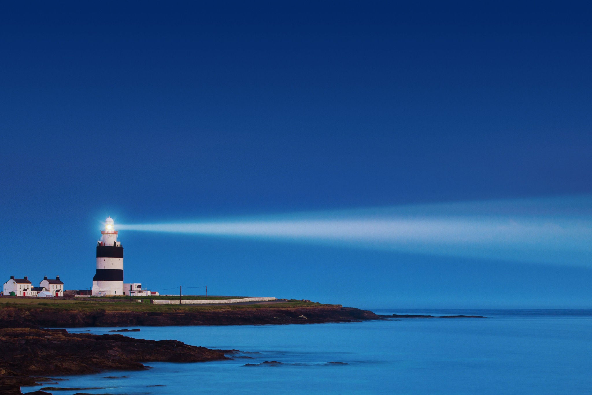 Phare projetant un faisceau lumineux sur la côte au crépuscule