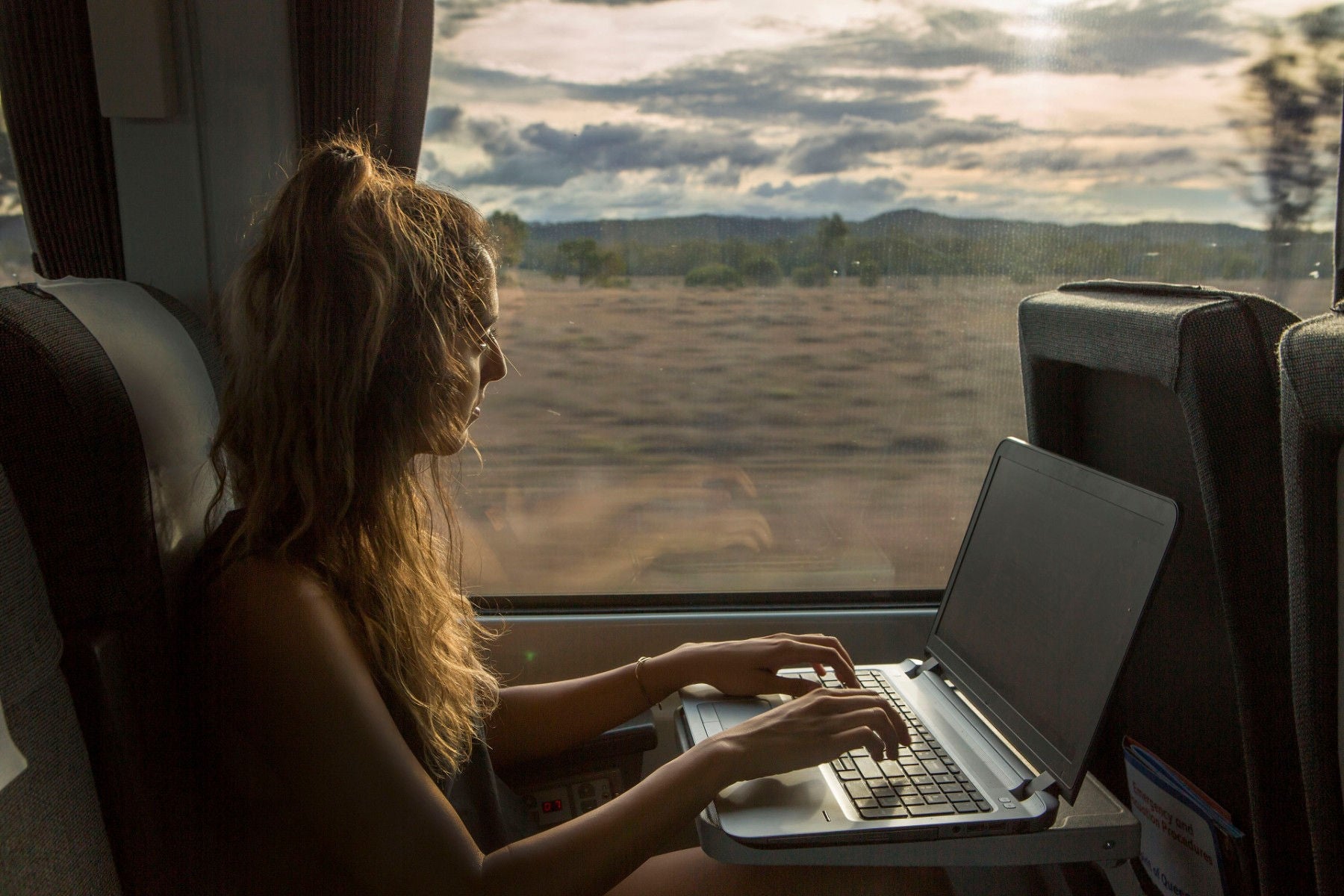 Woman works on her laptop while traveling on-a train