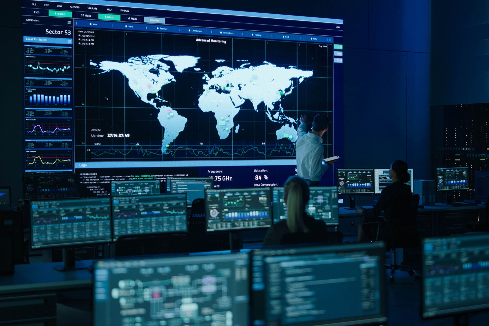 Project Manager Uses Digital Tablet Looks at Big Screen Display Showing Infographics and Global World Map Data. Telecommunications Control Monitoring Room with People Working