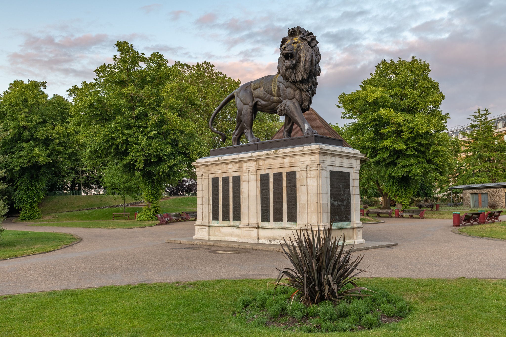 Lion statue on stone plinth in landscaped park