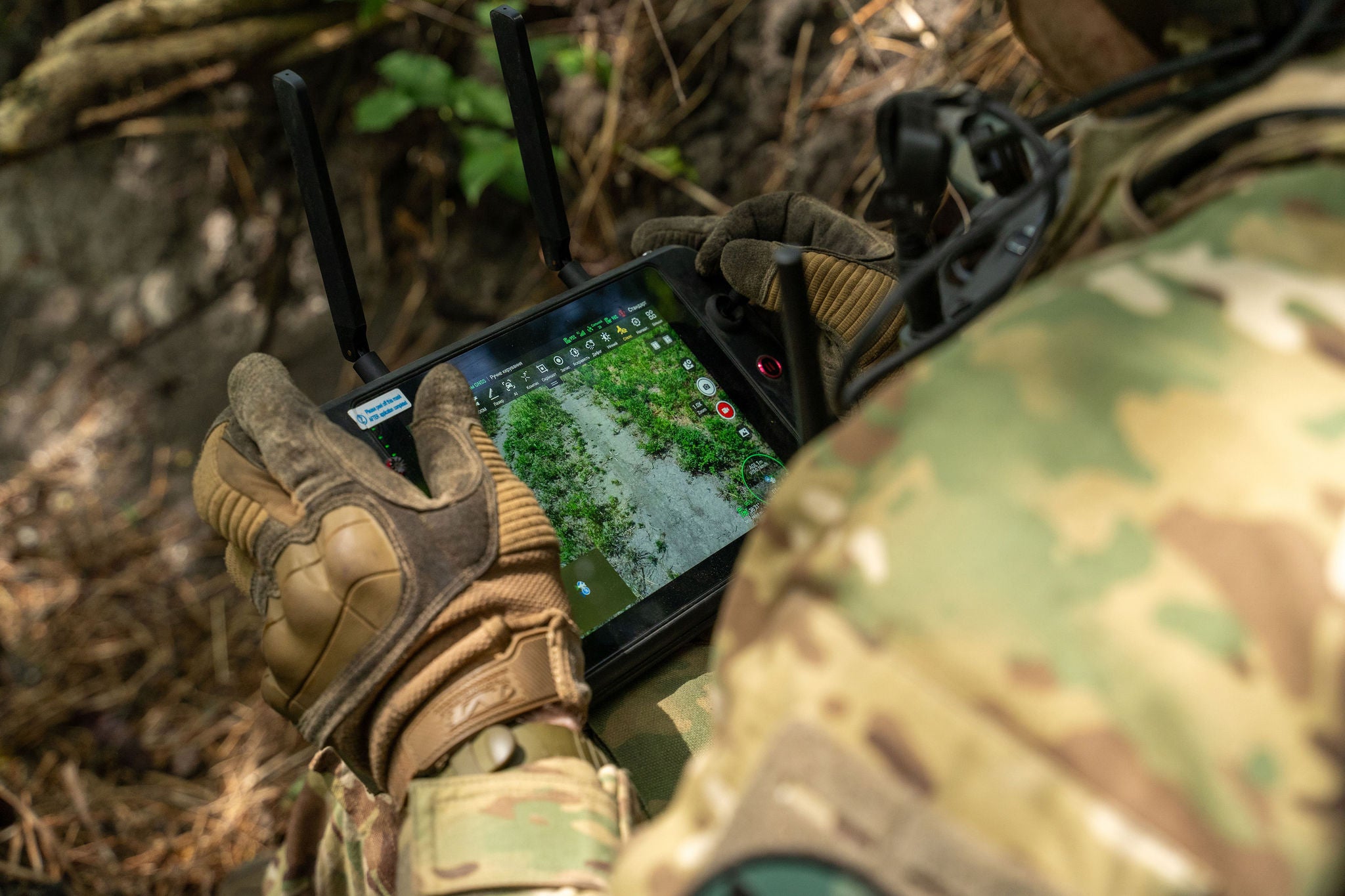 Soldaat in camouflage gebruikt een tablet met een kaart buiten