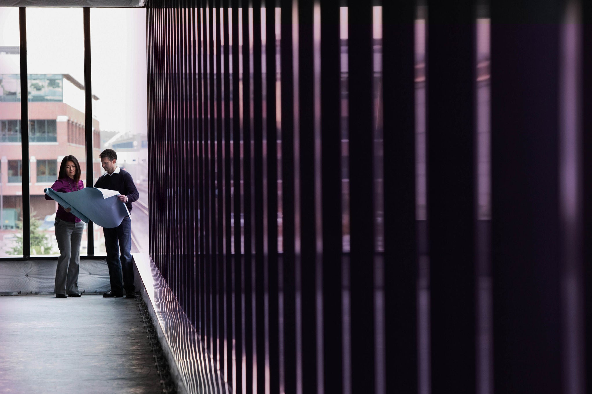 Two people reviewing large plans in a modern corridor