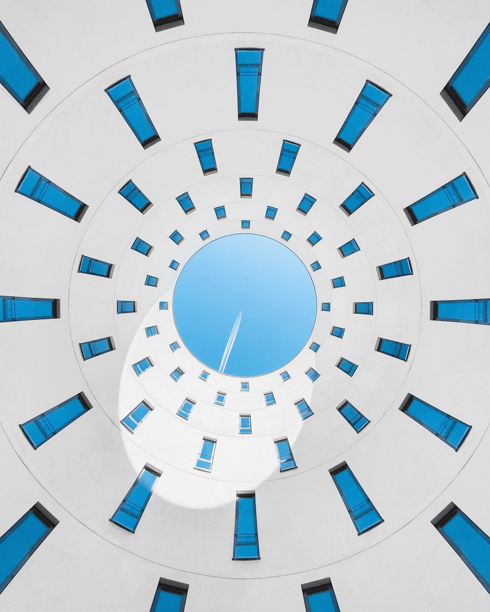 looking up at plane in the sky seen from a centeral building courtyard