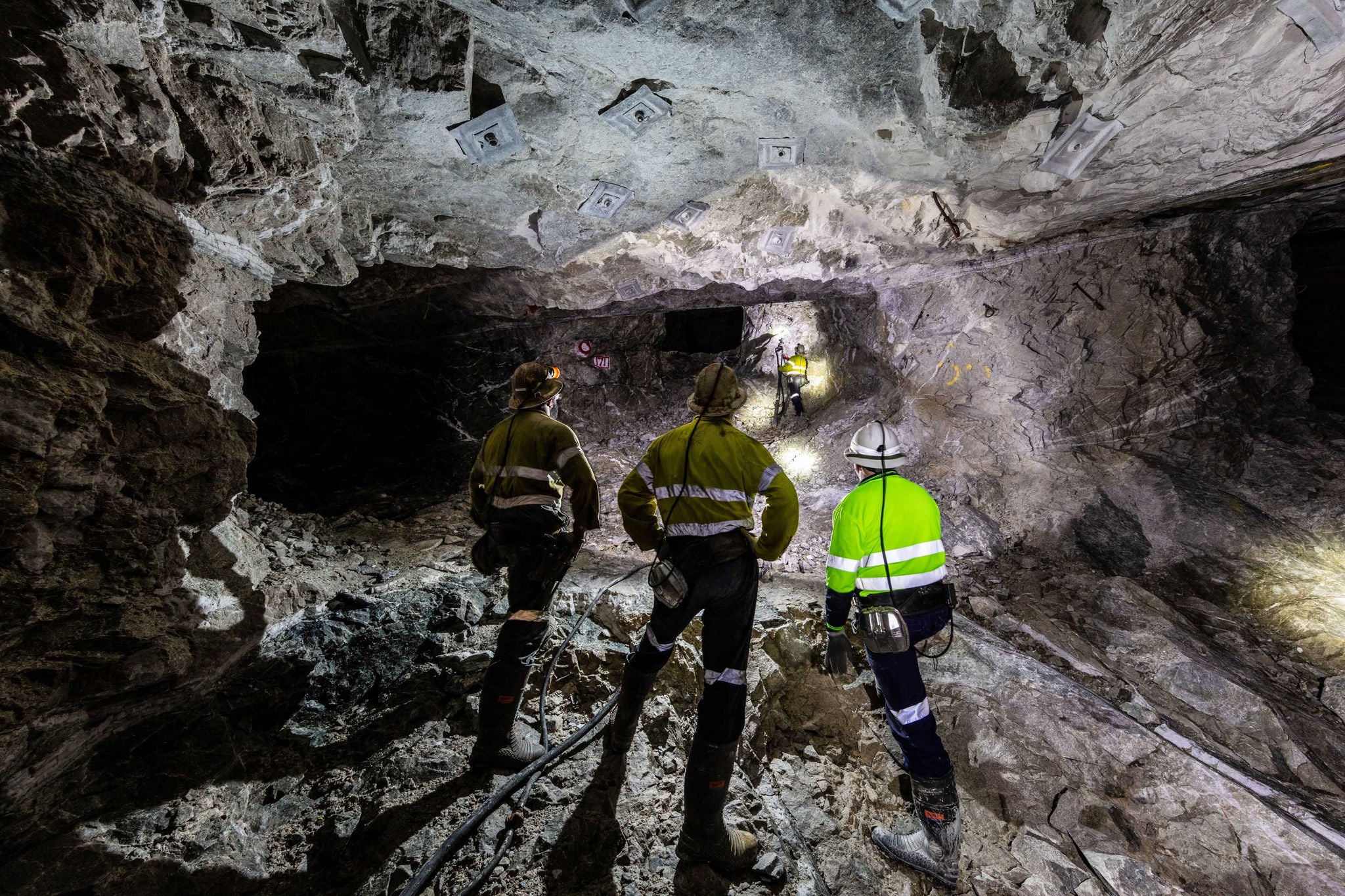 Workers in safety gear inspecting an underground mining tunnel