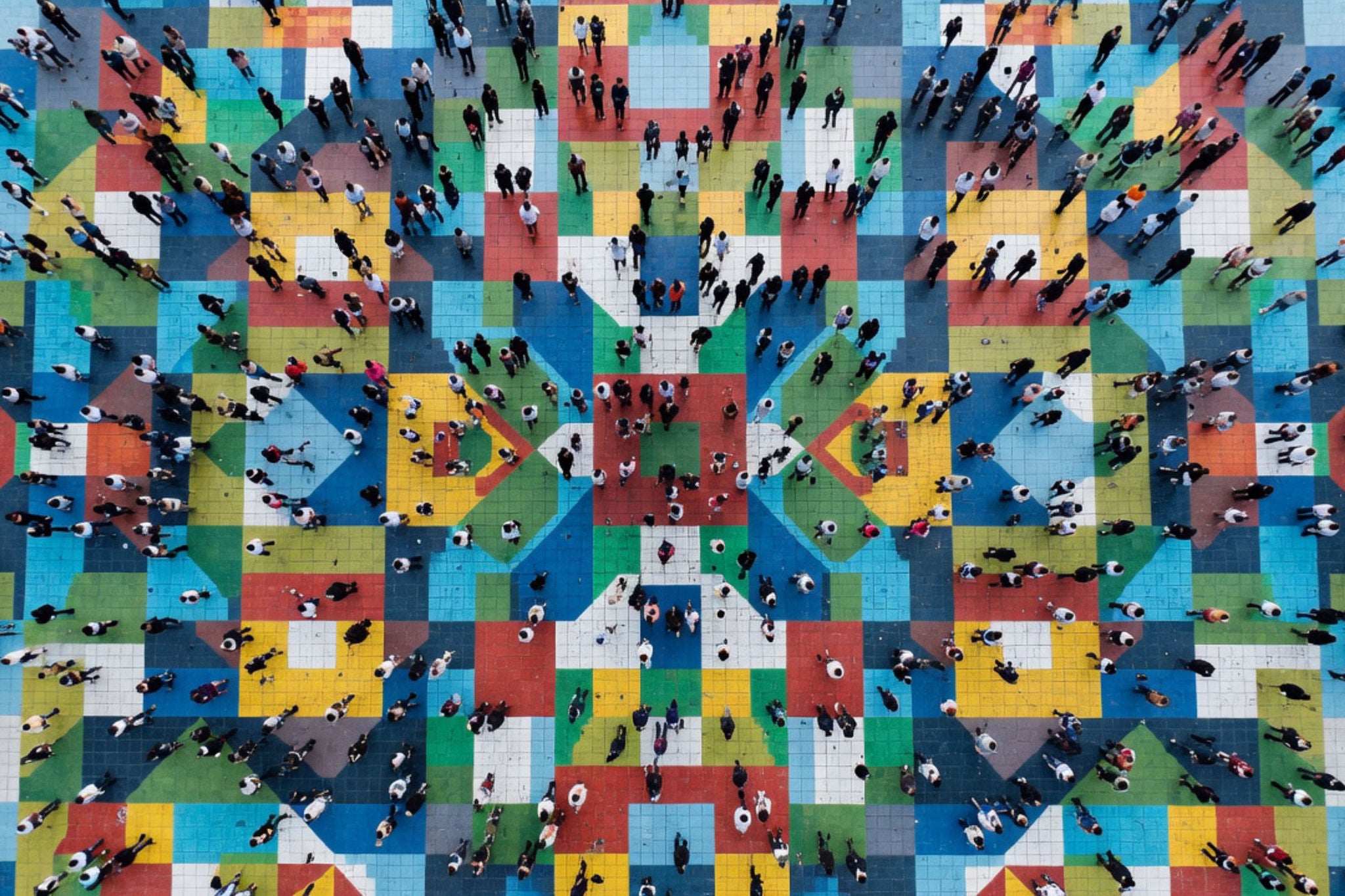 Aerial view of people walking on colorful geometric pattern.