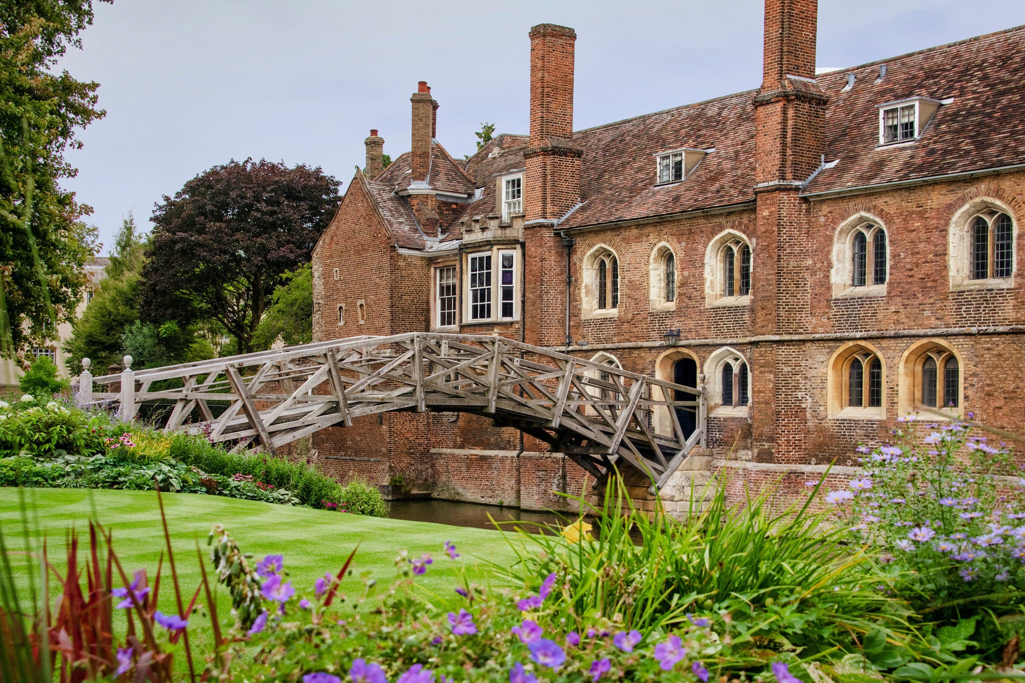 Wooden bridge crossing a river beside historic brick buildings