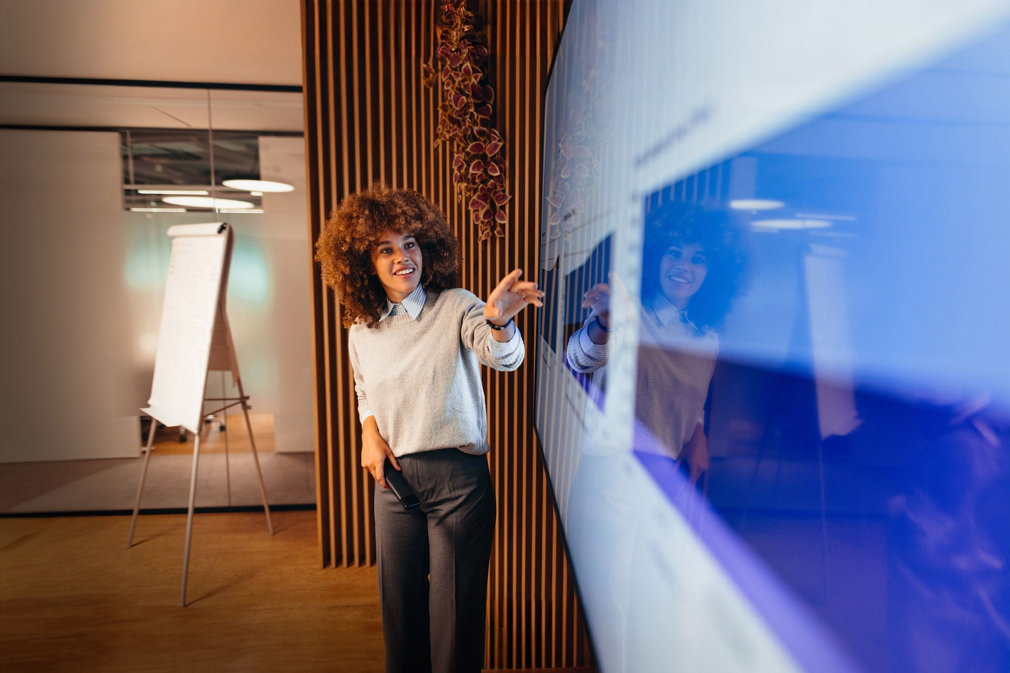 Young businesswoman engaging colleagues with a large interactive monitor