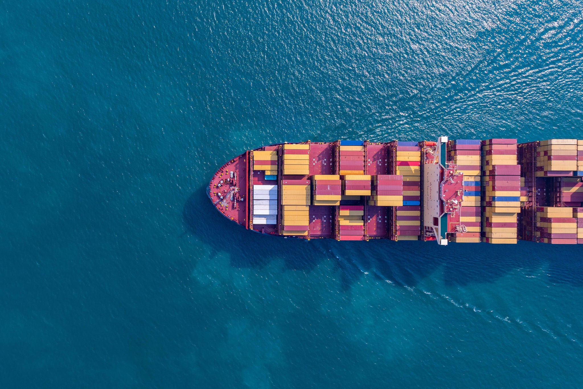 Aerial view of a container ship carrying freight across open waters, supporting global import and export logistics.