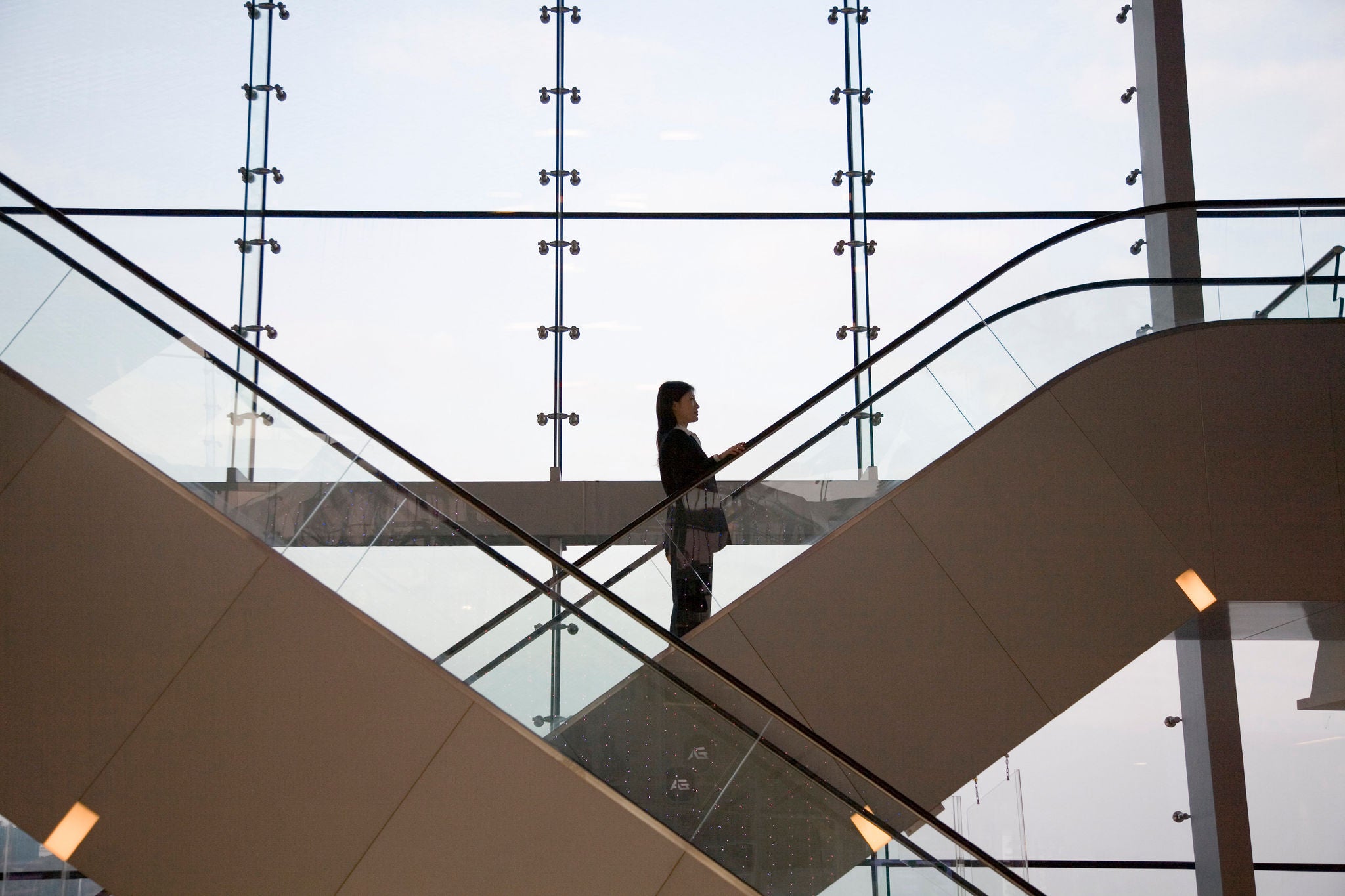 businesswoman going up escalator side view