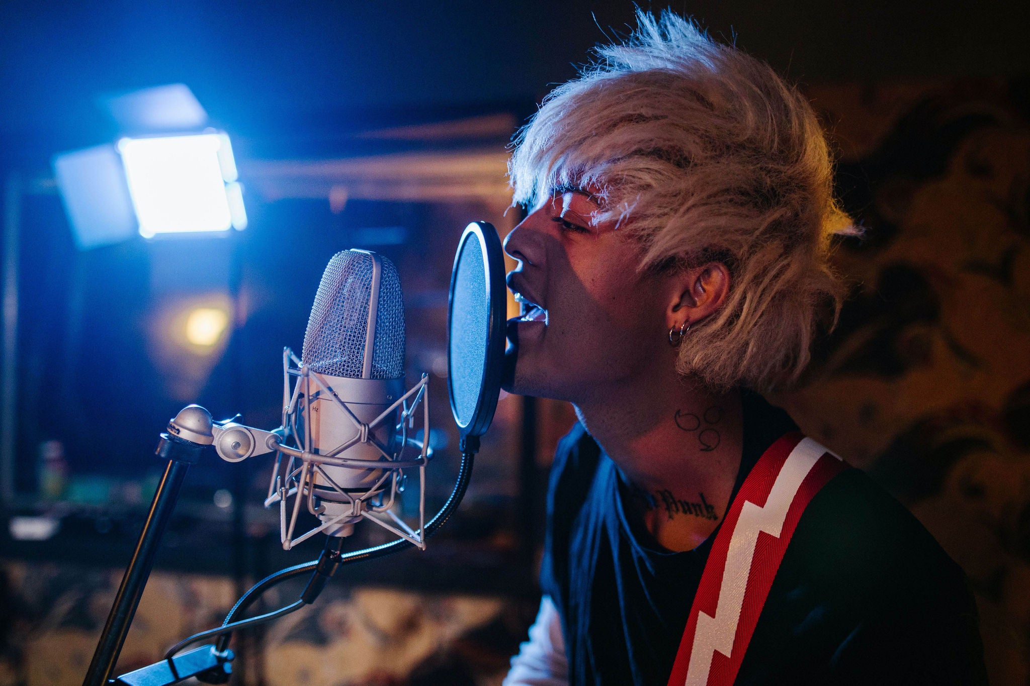 Blonde hipster singing into microphone in music studio, playaing guitar, Rodnae productions