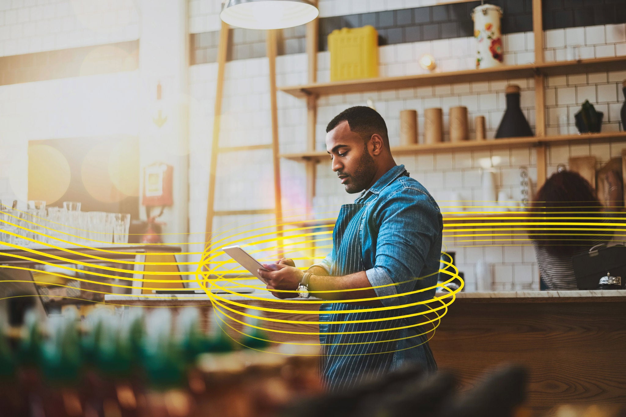  Focused manager on a tablet in a café, representing online entrepreneurship in retail, tech, food and coffee businesses.