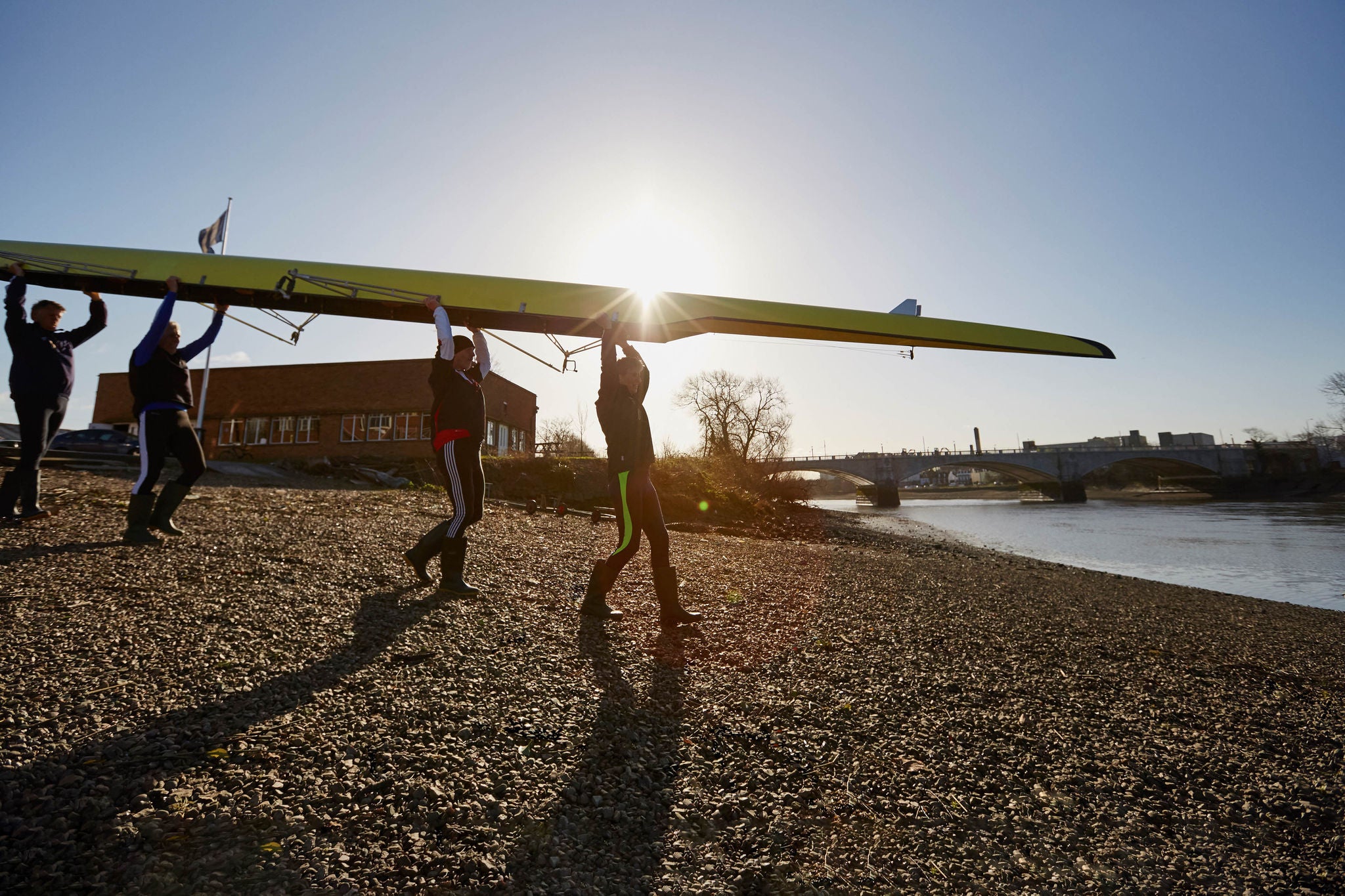 Rowers carry their boat above their heads to the water