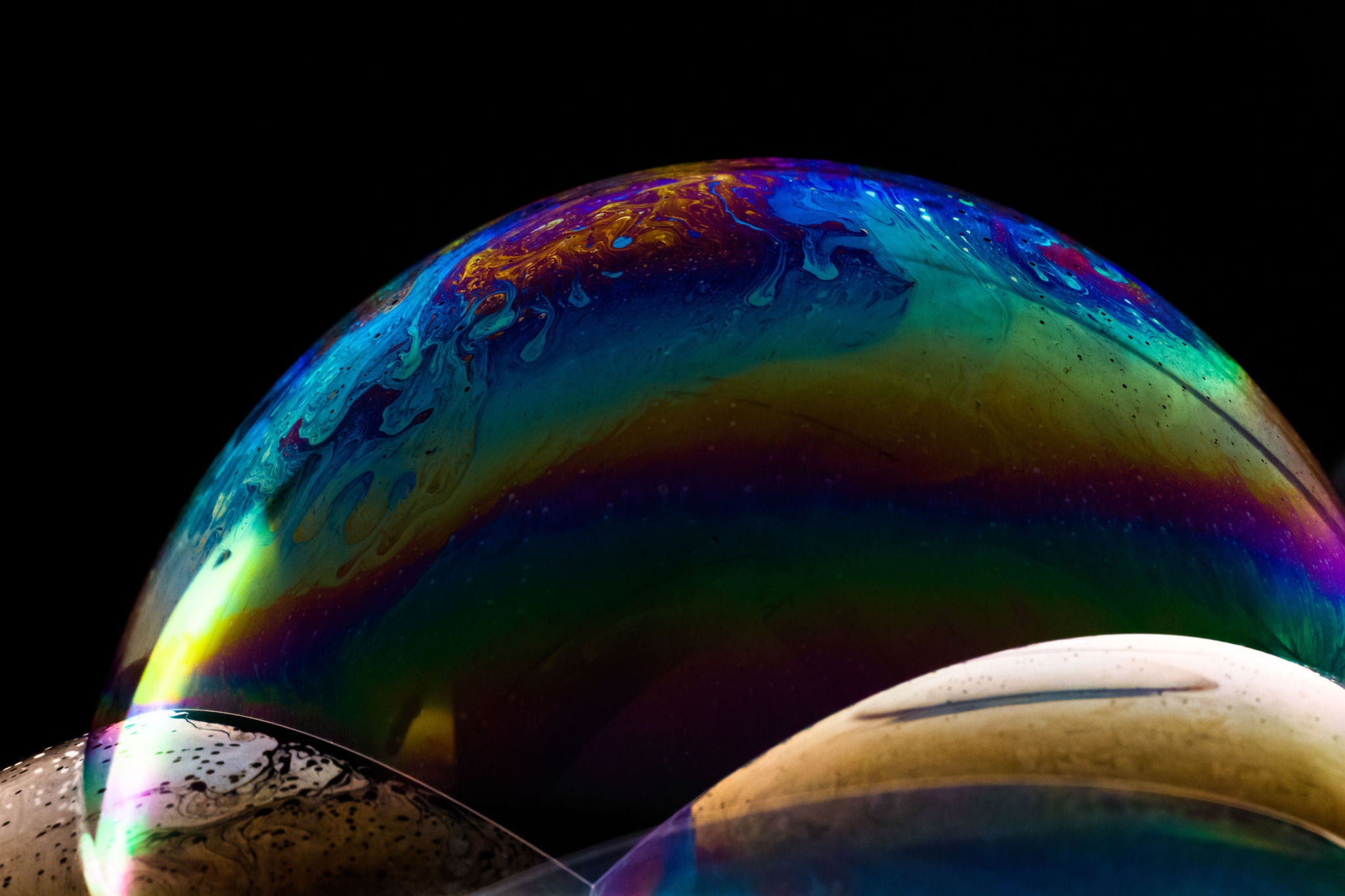 Close up of three stacked soap bubbles with rainbow colours and patterns