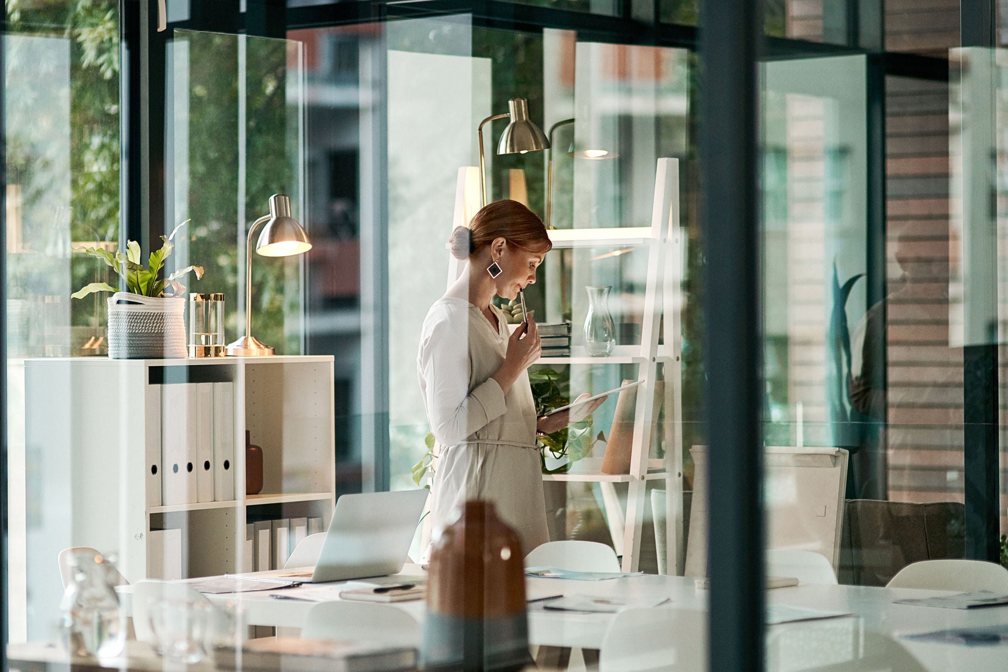 A modern office, building interior and a businesswoman doing online research on a tablet or looking at files. Female inside her corporate workplace architecture indoors preparing for a presentation