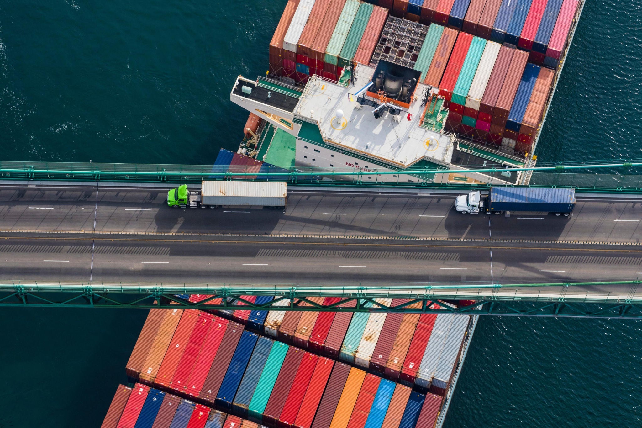 Large Container Ship crosses under a bridge at the port