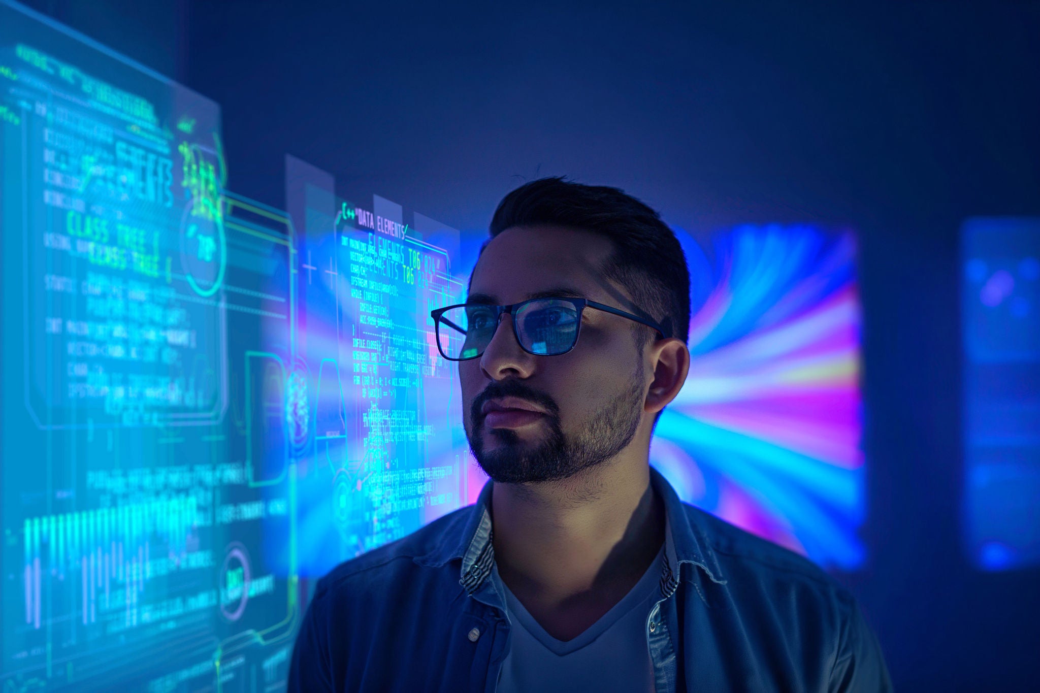 Developer wearing glasses works on transparent futuristic computer in a cyber security data center.