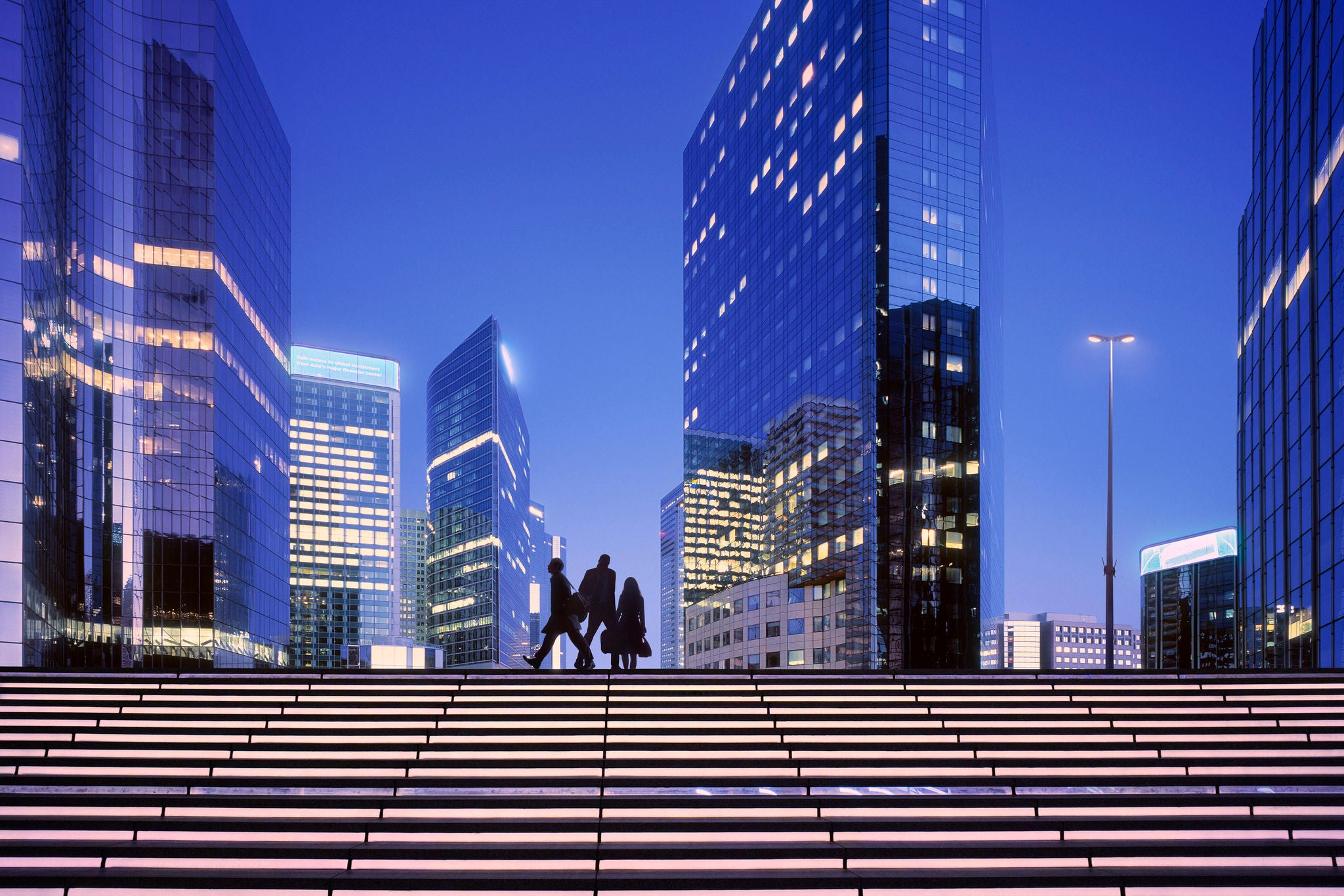 Morning image with businesswoman and businessmen arriving at modern business district.