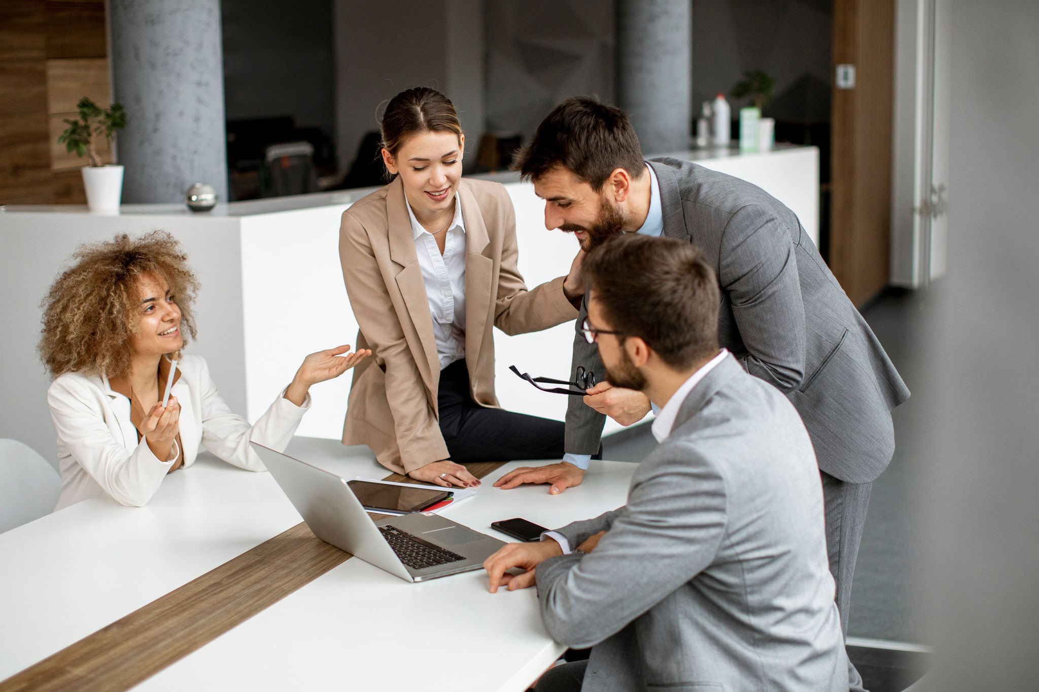 Corporate businesswoman communicating with team while sitting at desk in meeting room in office