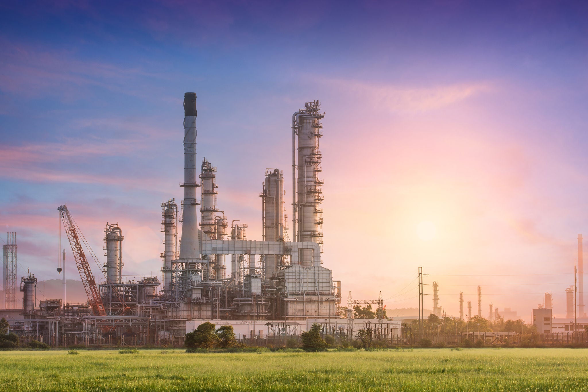 Raffinerie industrielle au lever du soleil avec tours et conduites.