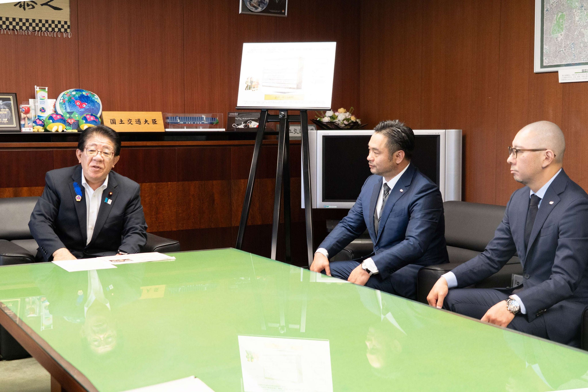 写真：金子 恭之 国土交通大臣への試算結果説明時の様子（EYSC撮影） （左から、金子 恭之 国土交通大臣、 EYSC　クライアント・アンド・インダストリー・リーダー　パートナー　菅田 充浩、 自動車・モビリティ・運輸・航空宇宙・製造・化学セクター　パートナー　小池 雄一）