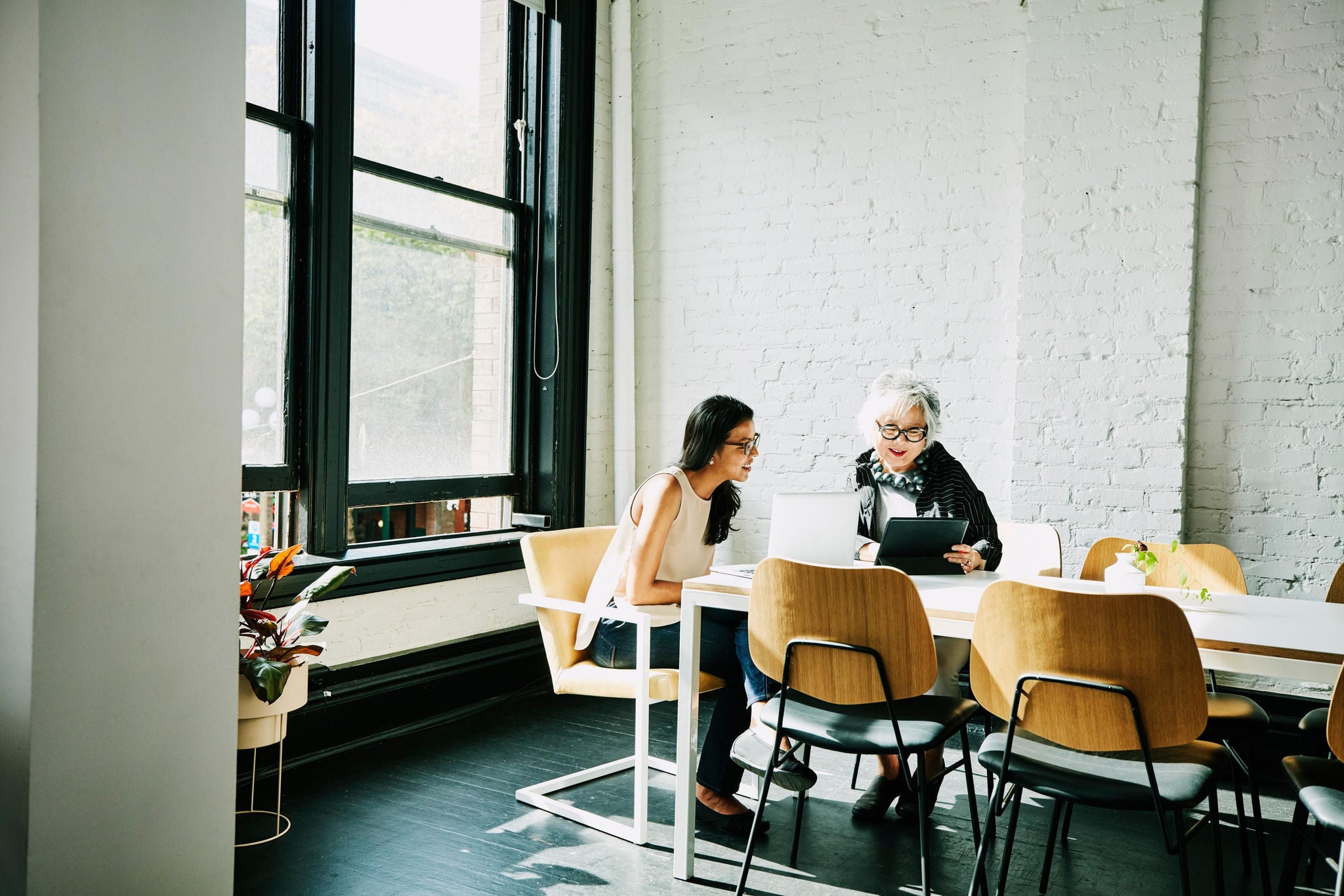 Two coworkers having a meeting in an office holding a digital tablet