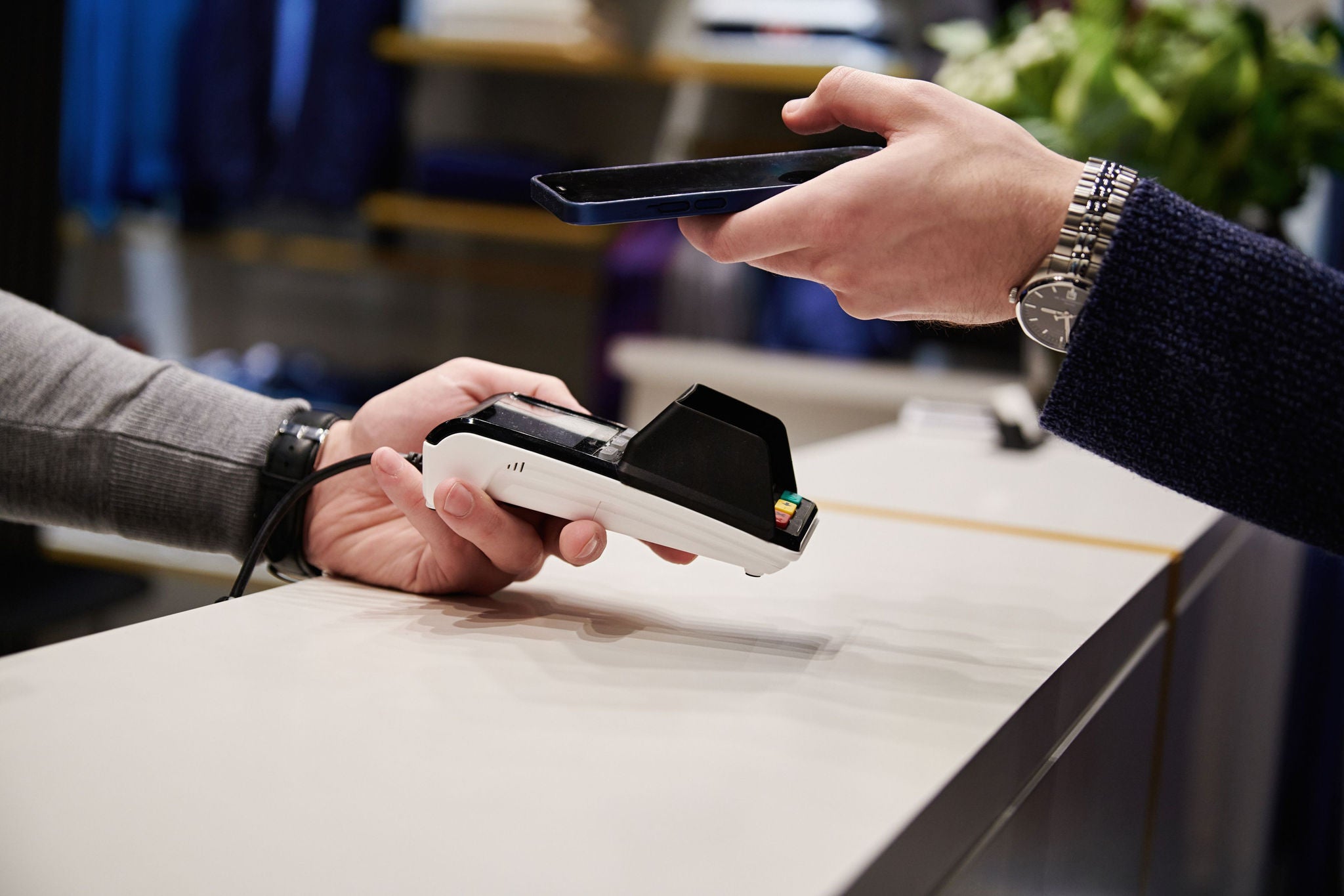 Contactless payment using a smartphone and card reader at a checkout counter.