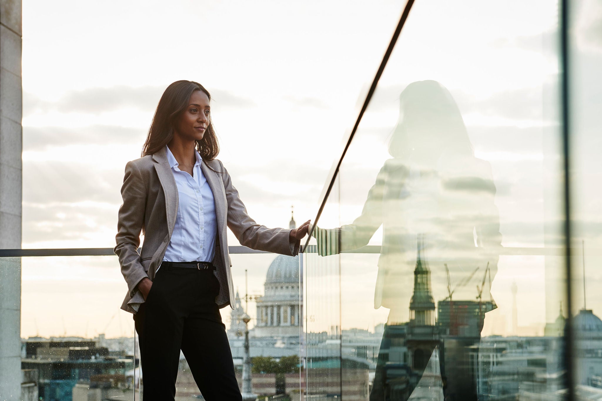 Businesswoman on a balcony looks over the city of london