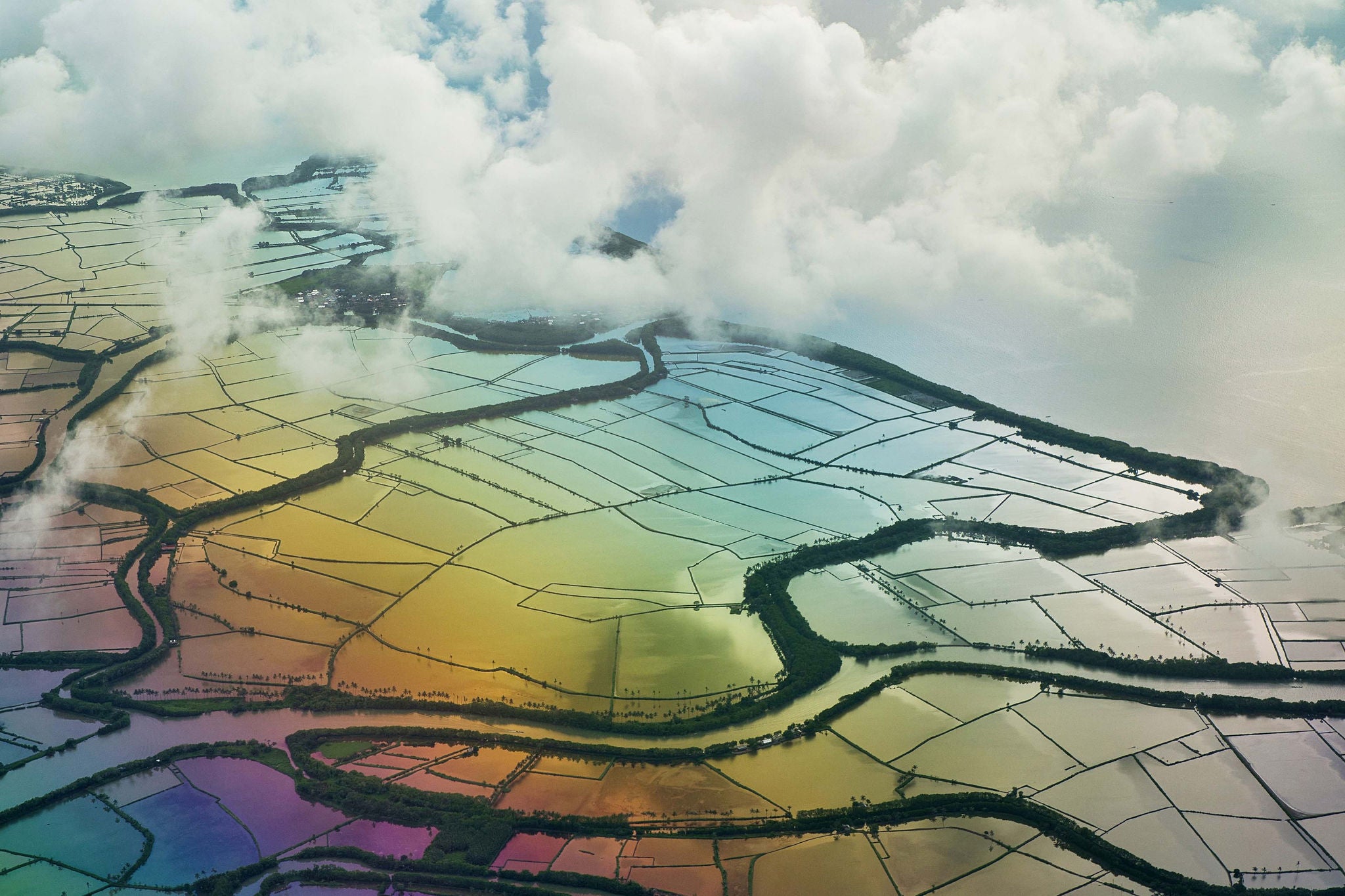 Spectacular drone view of agricultural rice paddies with water reflecting colorful sky and clouds