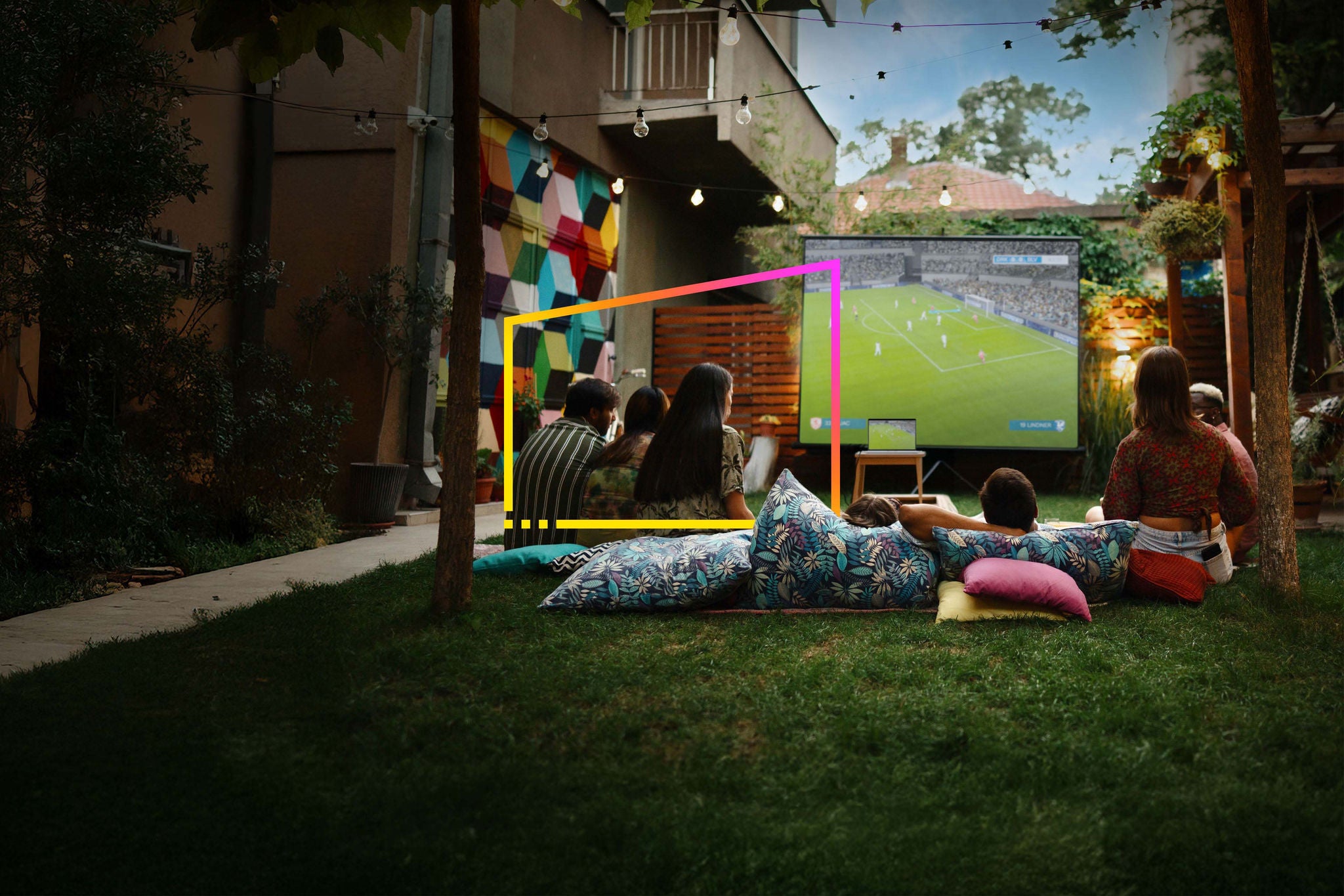 Joyful friends watching movies on a projection screen  in the backyard