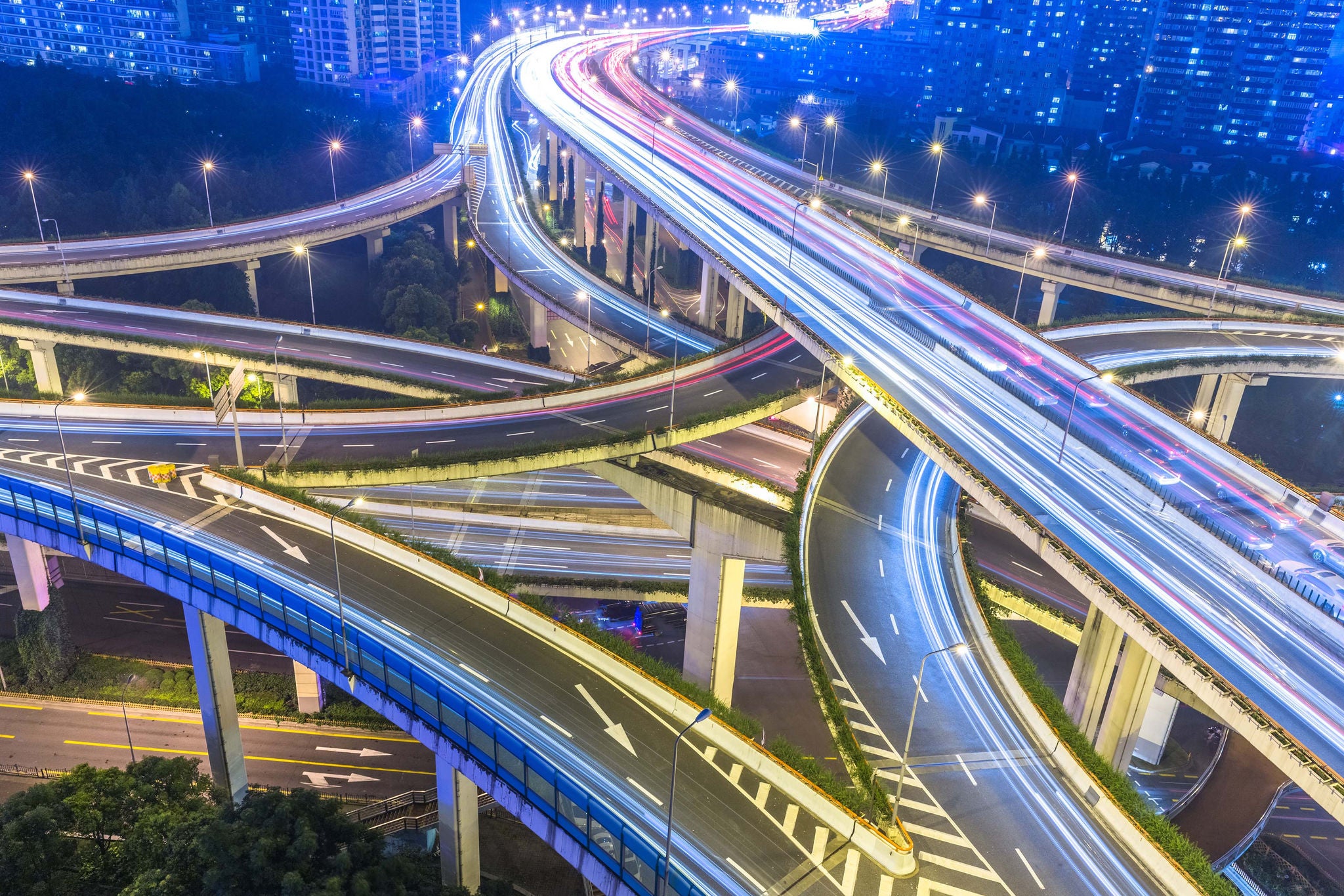 Aerial view of a busy highway interchange with light trails from traffic at night.