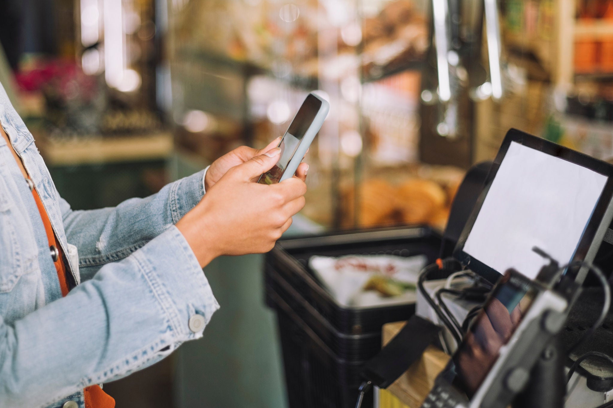Woman using smart phone while scanning QR code for payment at store checkout