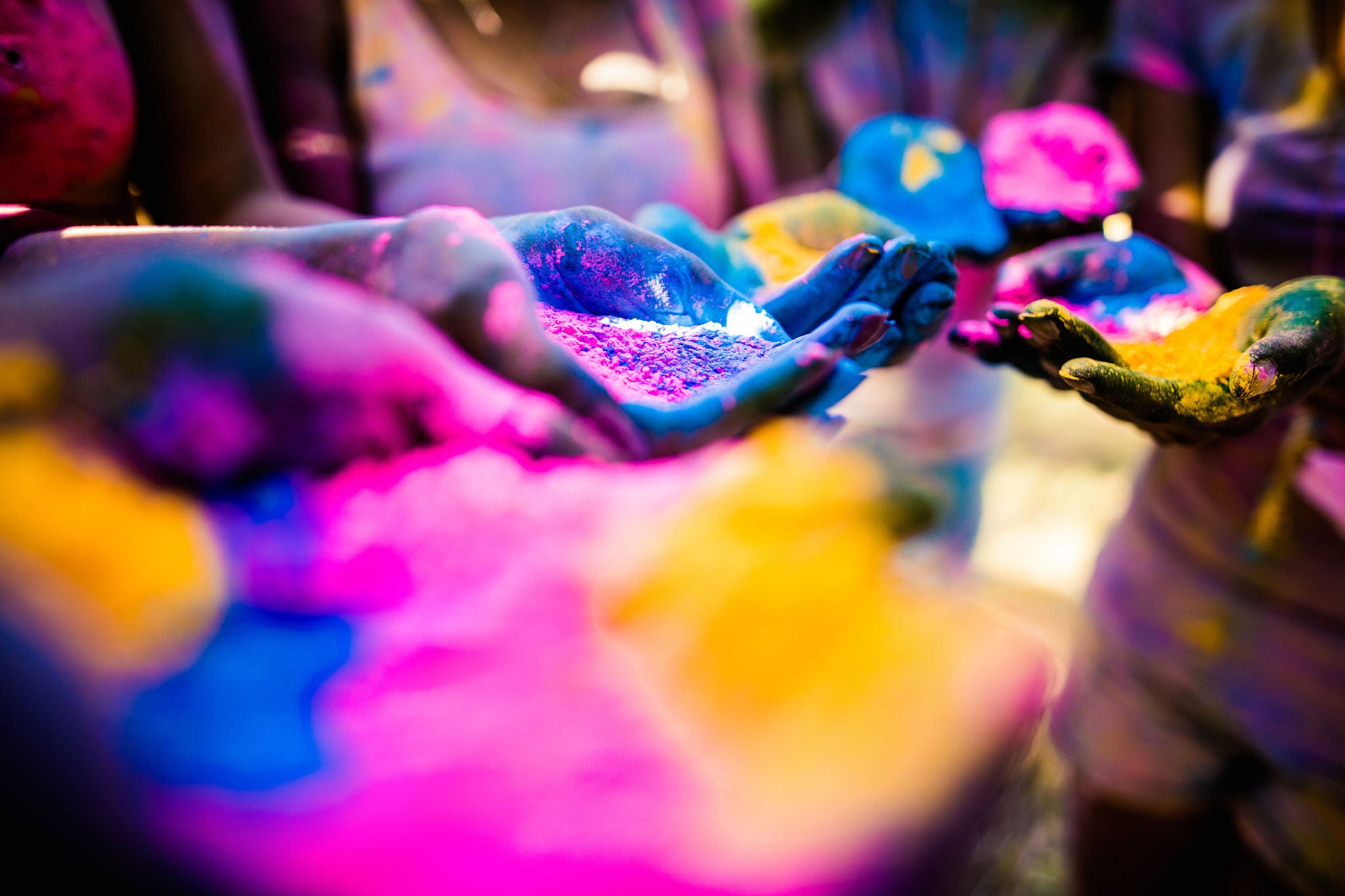 Group shot of hands covered in colors, holding colorful powder during a Holi festival in a park