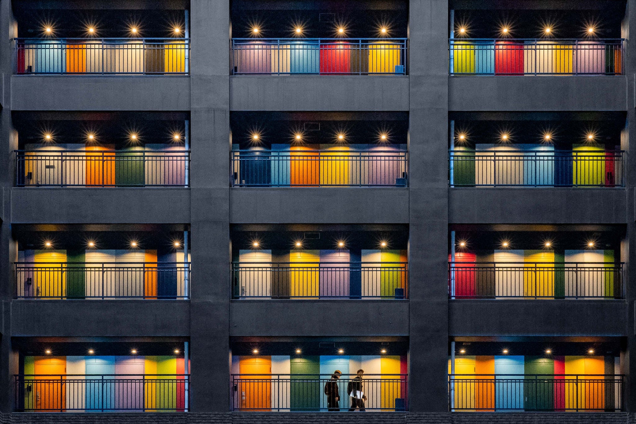 Ihmisiä kävelee kerrosten värikkäissä rappukäytävissä