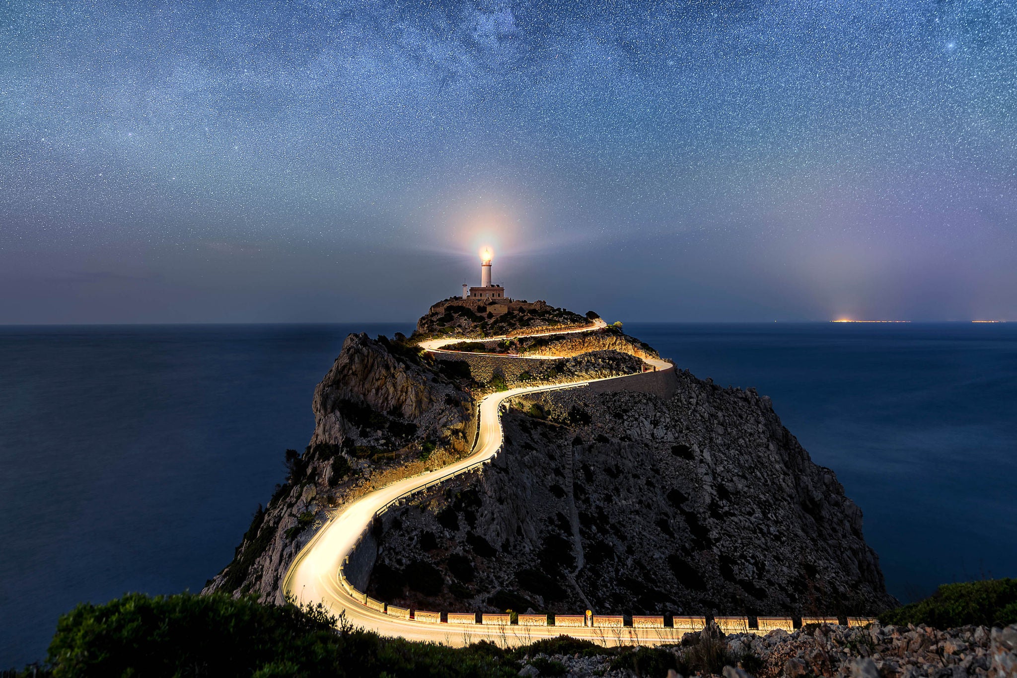 Oplyst vej der fører op til lysende fyrtårn set i mørke
