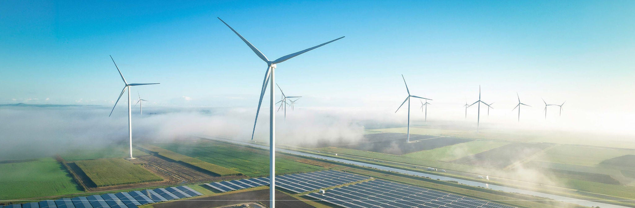 Windräder und Solarpark in weiter Landschaft mit Nebel, moderne saubere und nachhaltige Energie‑Infrastruktur