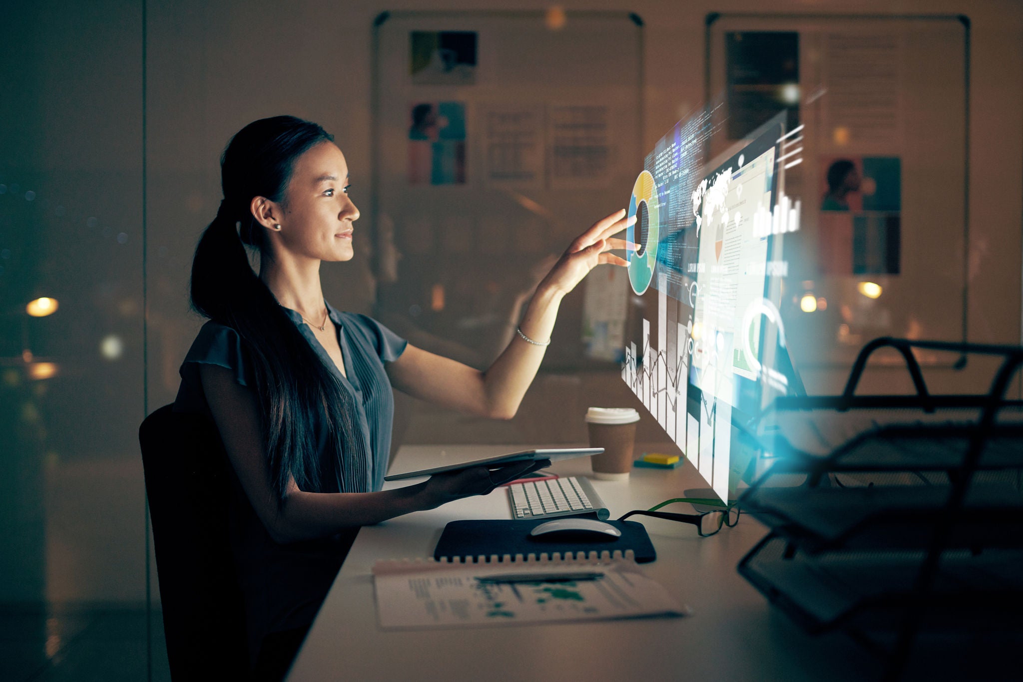 Shot of a young programmer using a digital tablet and computer at night in a modern office