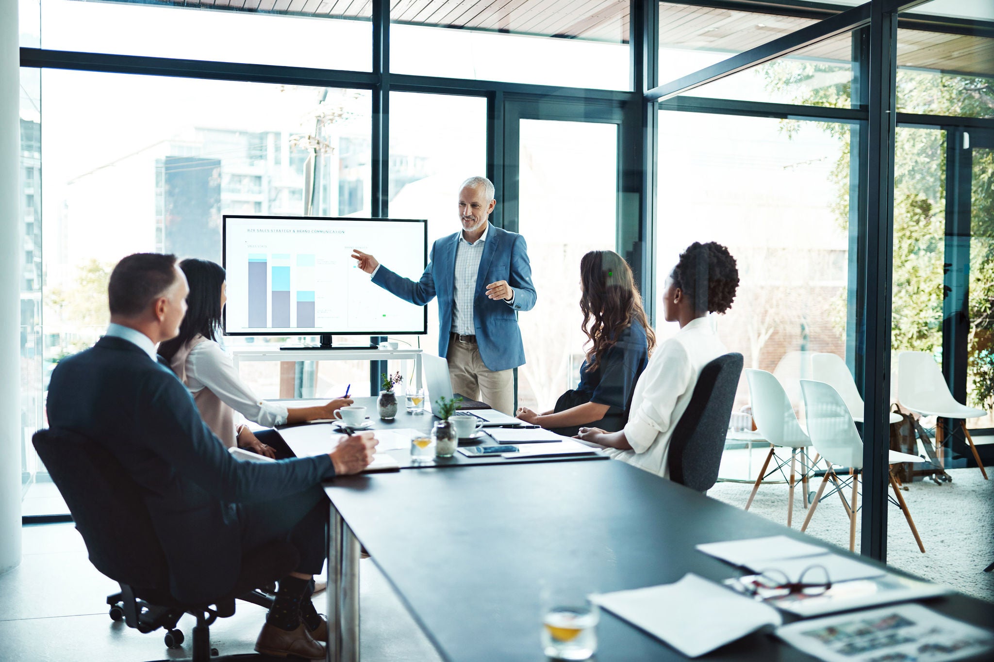 Person presents a chart on a screen during a meeting in a modern office