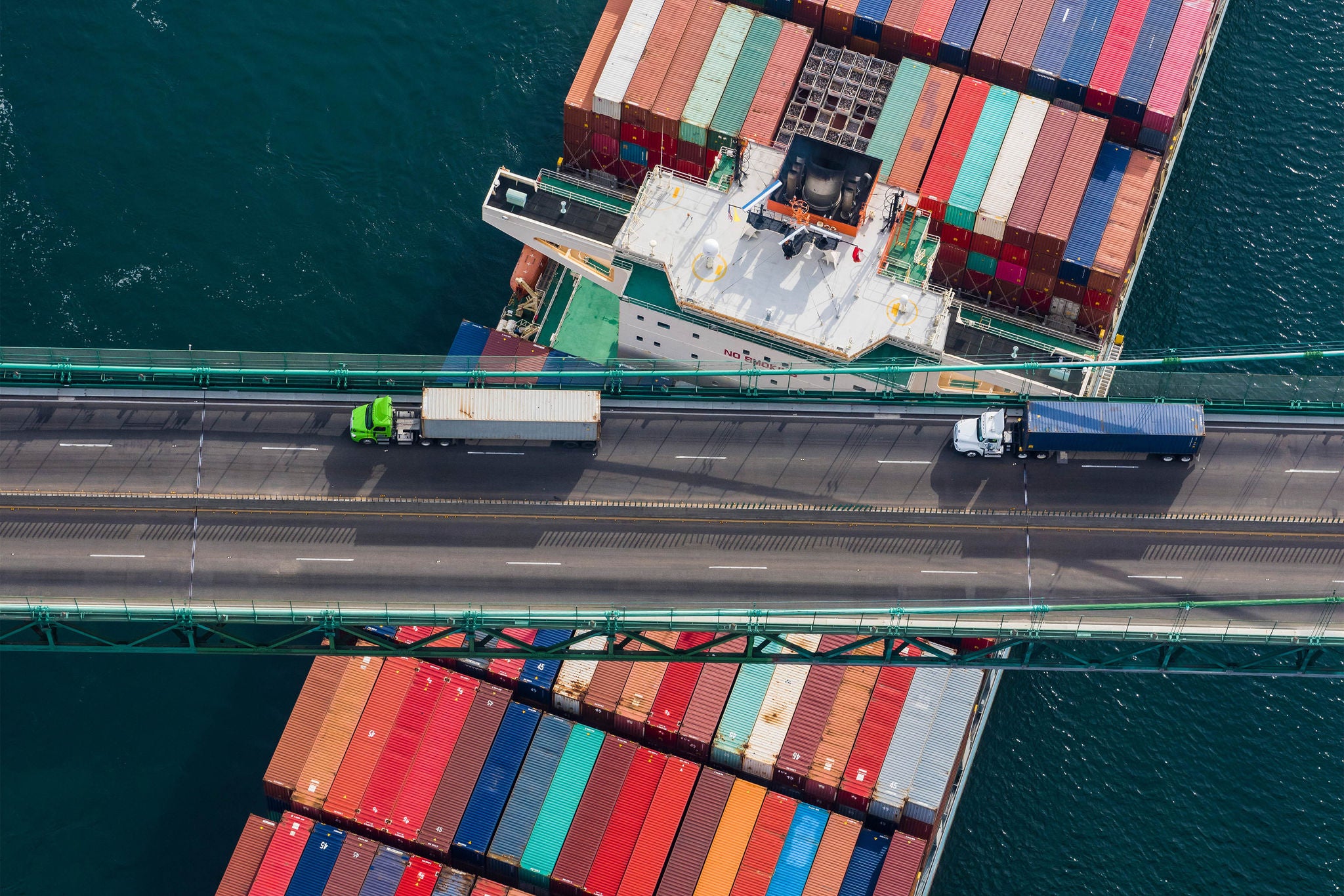 Suuri konttialus kulkee sillan alitse satamassa